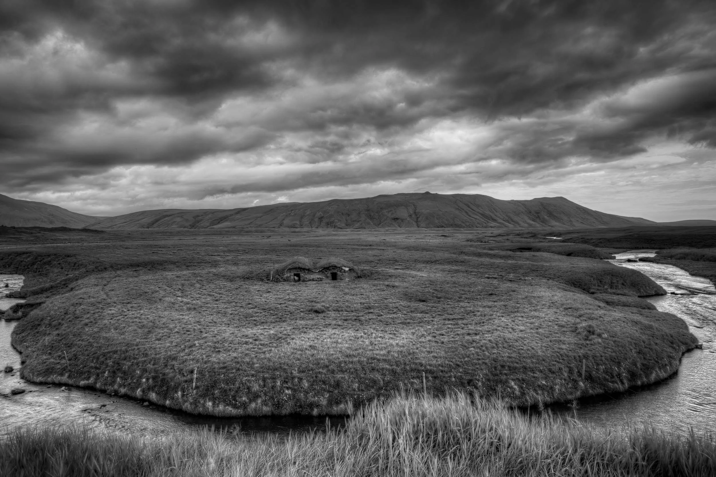 A distant sheep shelter in an extremely lush, well watered pasture in rural Iceland .