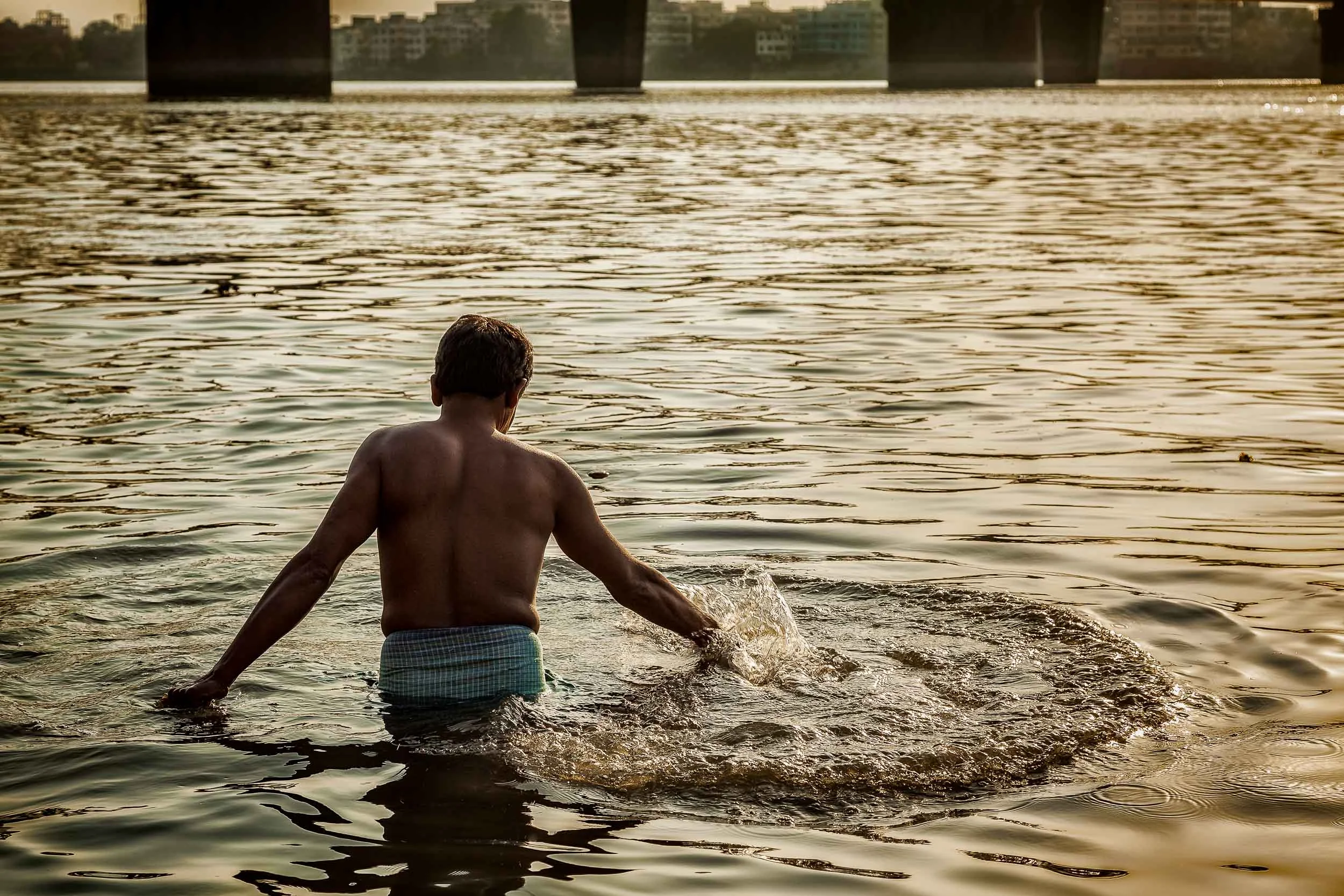 A devotee in a moment of rapture in the Hooghly River at sunset in Kolkata, India .