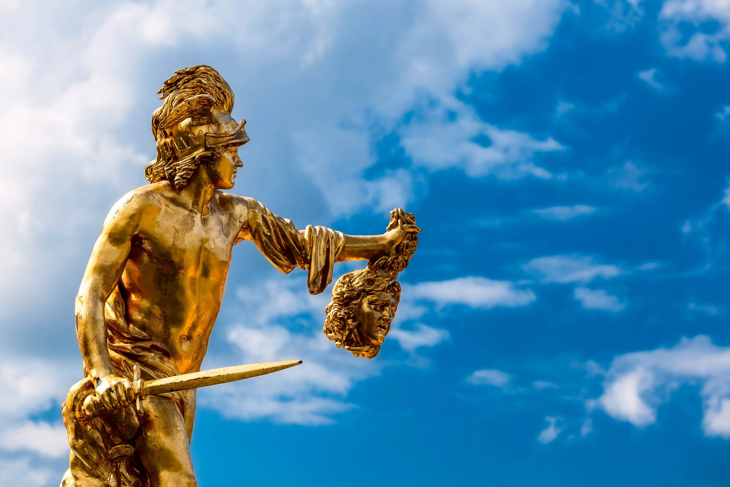A golden warrior statue holding the head of a victim in the grounds of Peterhof Palace near St. Petersburg, Russia .