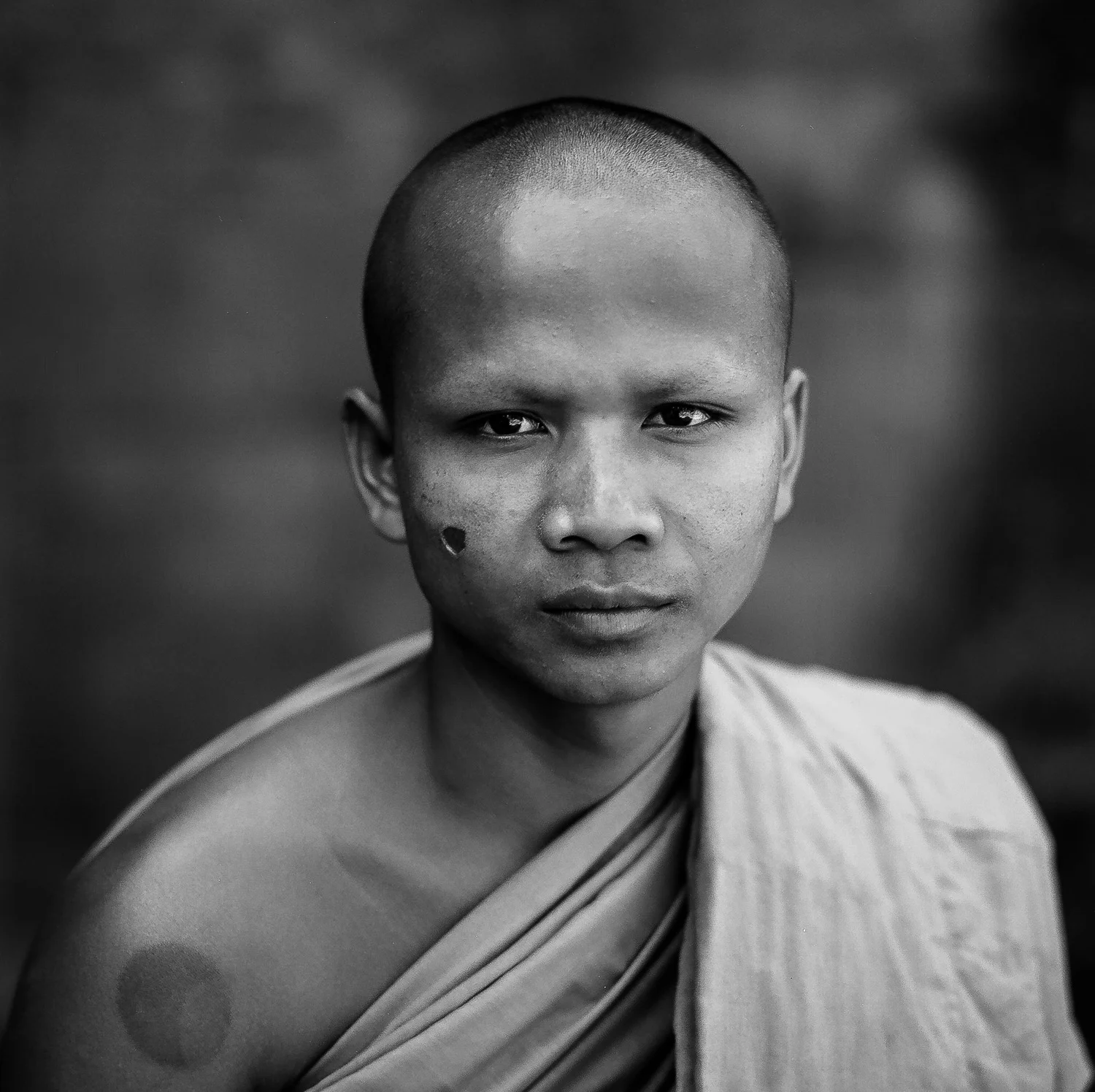 A formal portrait of a monk at the Bayon in the Angkor Wat complex near Siem Reap, Cambodia . The scare on his face is the result of being tortured , with a cigarette, by the Khmer Rouge when he was a child.