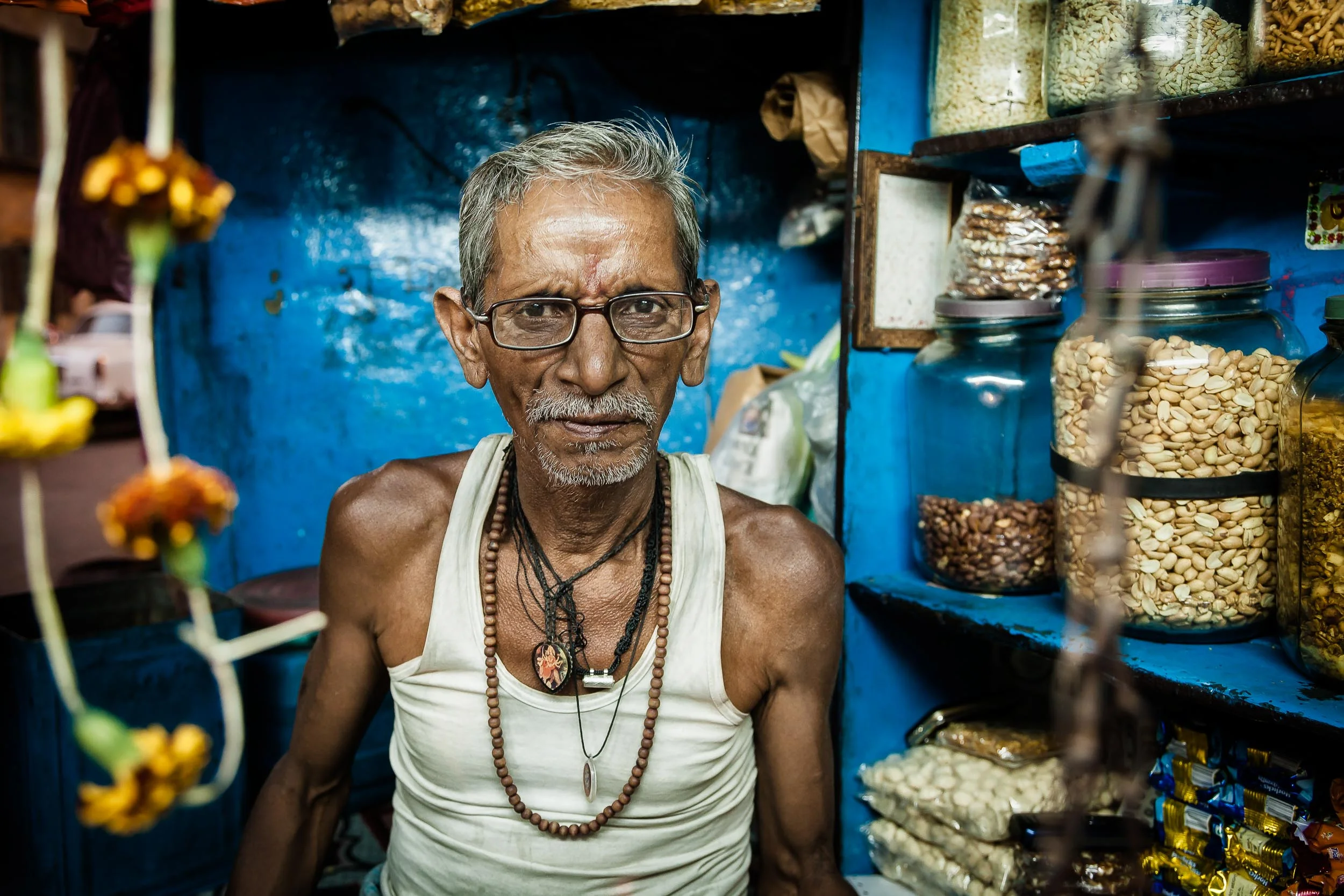 Environmental Portrait of a shopkeeper in his tiny, colorful shop in Kolkata, India .