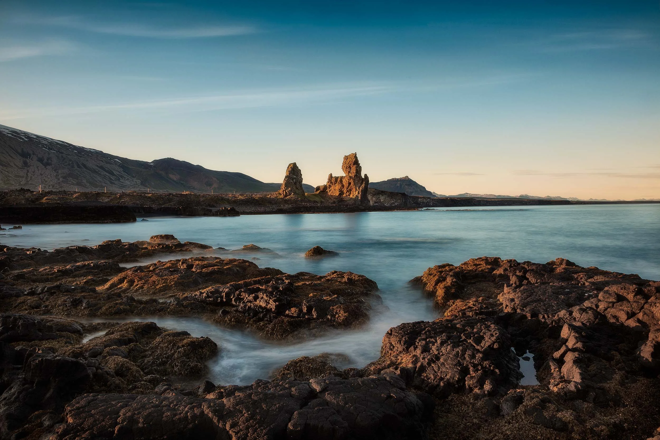 Rock formations come alive with the warm light of sunset by the coast in northern Iceland .
