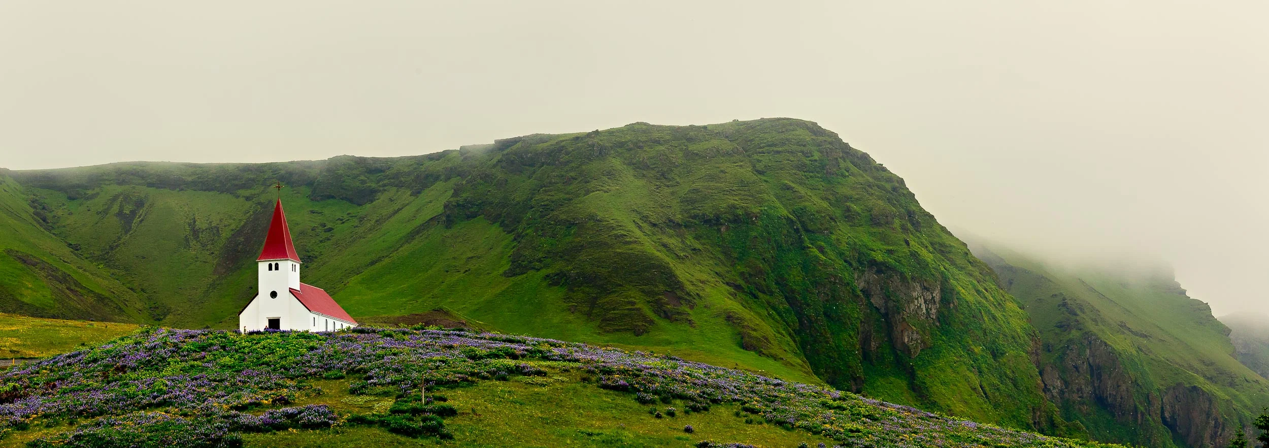 A spectacular panoramic view of the Vik Luthern Church on a hillside above the town. At around 300 inhabitants Vik is the southern most town in Iceland .