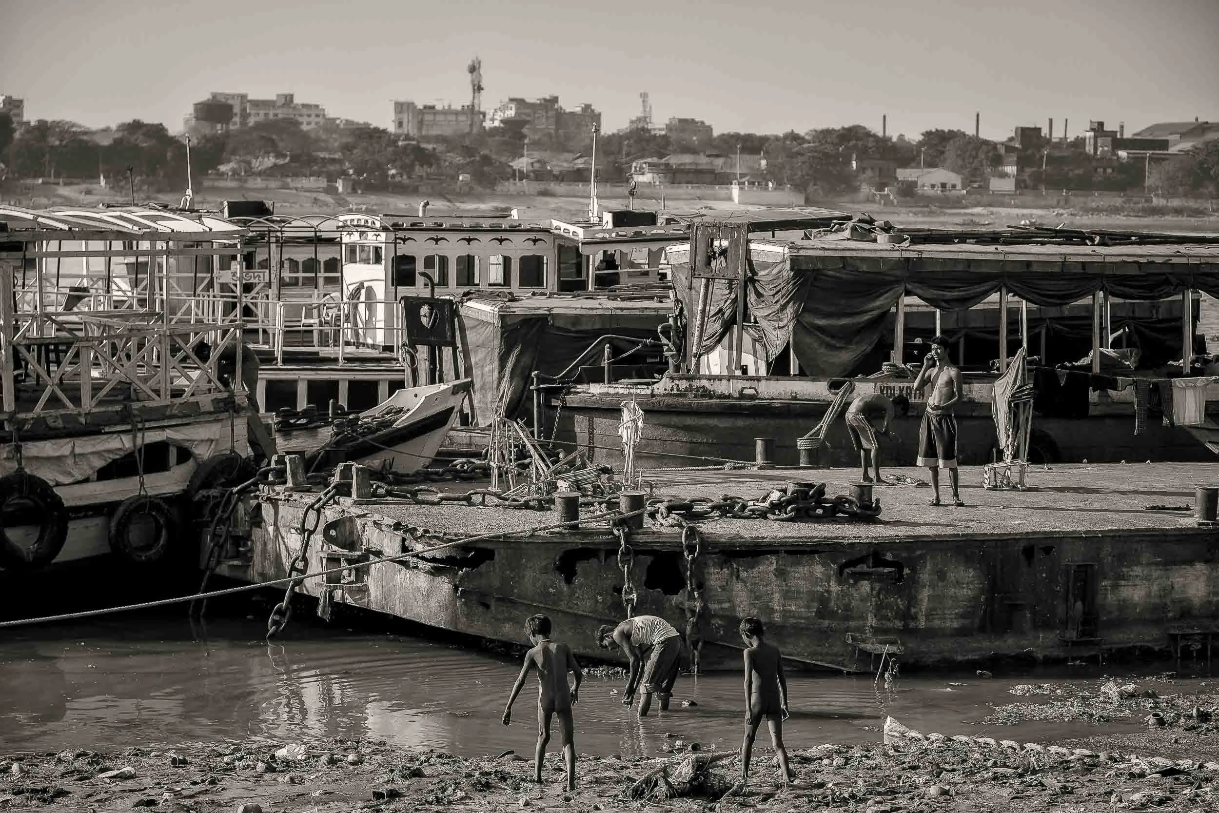 Young boys and workers by the banks of the Hooghly River in Kolkata, India .