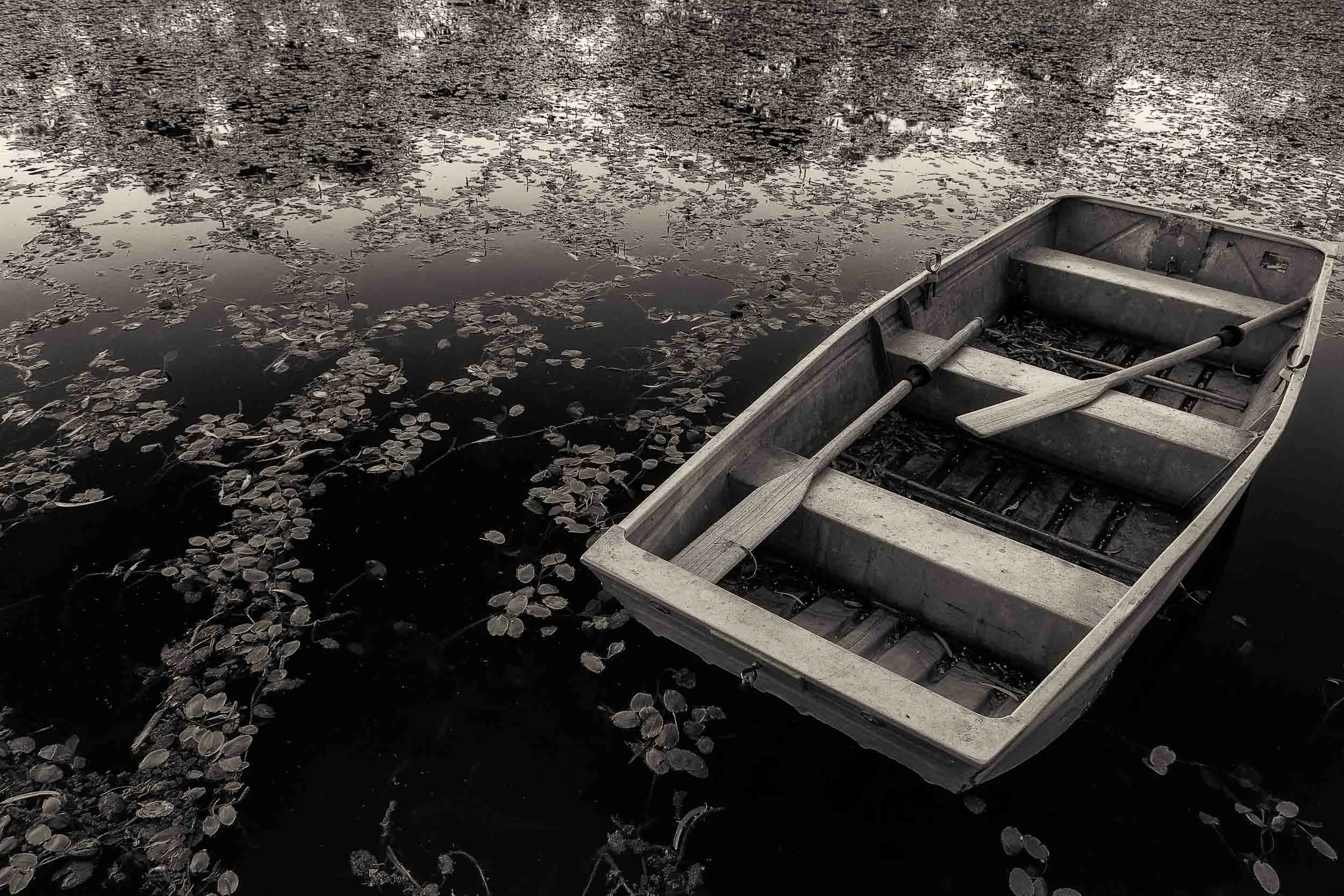An old row boat drifts aimlessly on placid waters on a warm, dreamy day near Mildura in Australia .