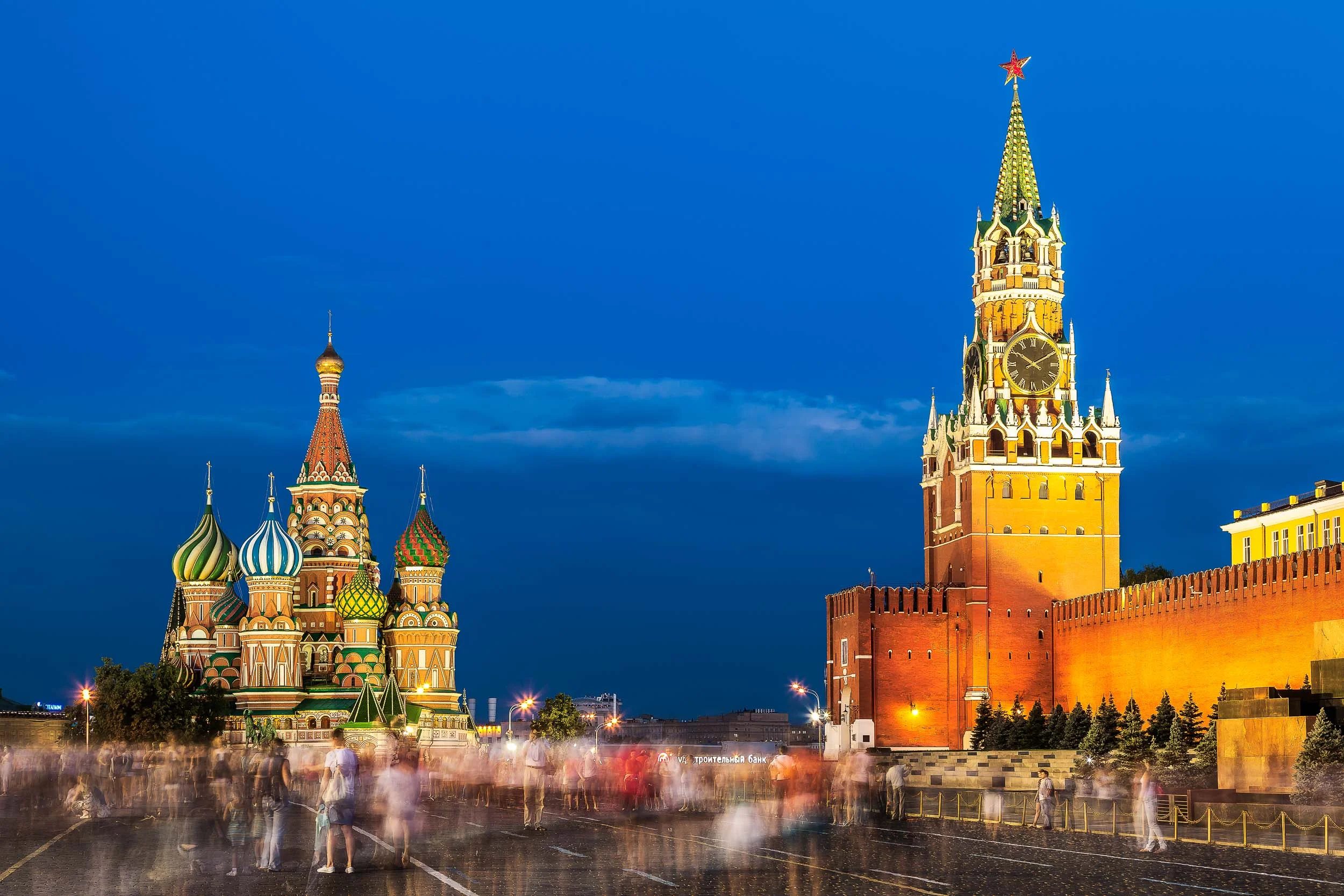 The crowd moves silently through the spectacular Red Square in Moscow , Russia on a balmy summer evening flanked by the magnificence of St. Basil's Cathedral and the Kremlin .