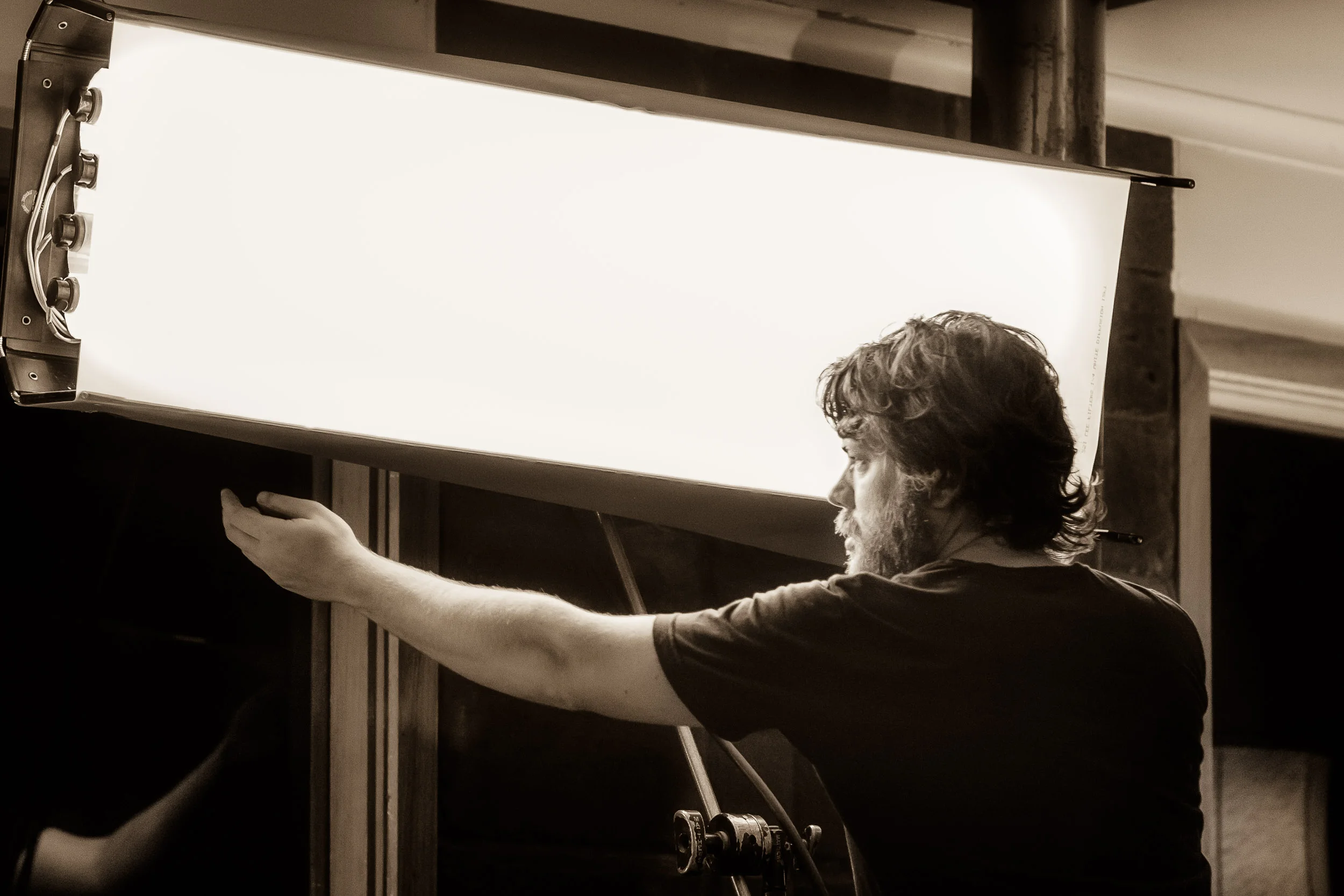 Lighting assistant Birren adds diffusion to a bank of fluroescent lights on the set of Summer Coda on a farm near Buronga in NSW.