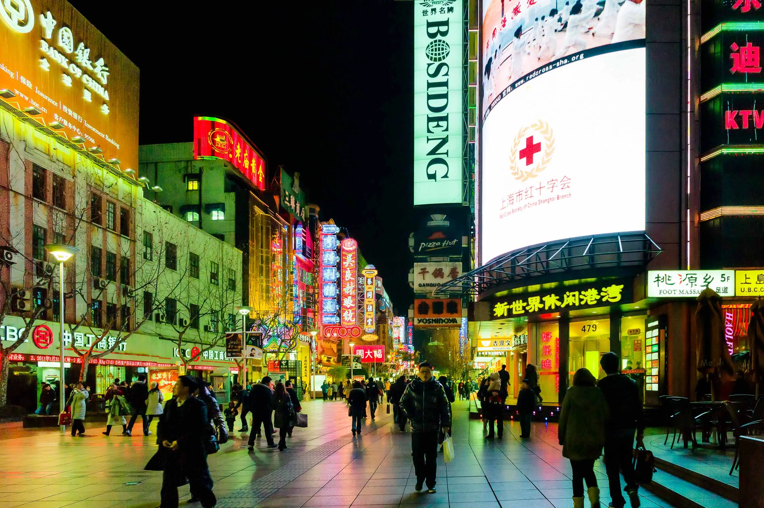 Pedestrians making their way along neon lit Nanjing Road in Shanghai, China.