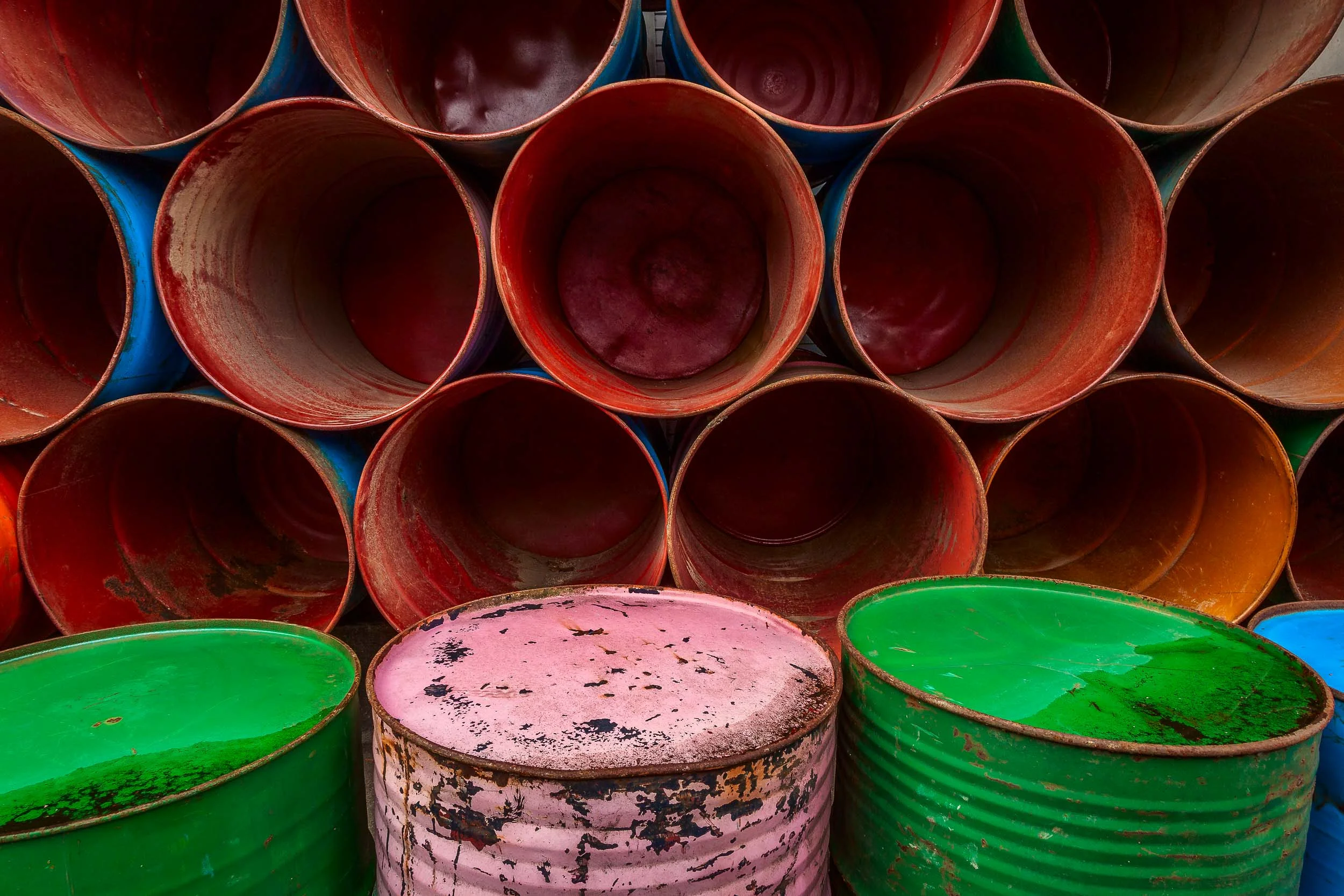 An arrangement of colorful barrels , stacked by the side of the road in Ubud, Bali make for a vivid, symmetrical and well balanced composition.