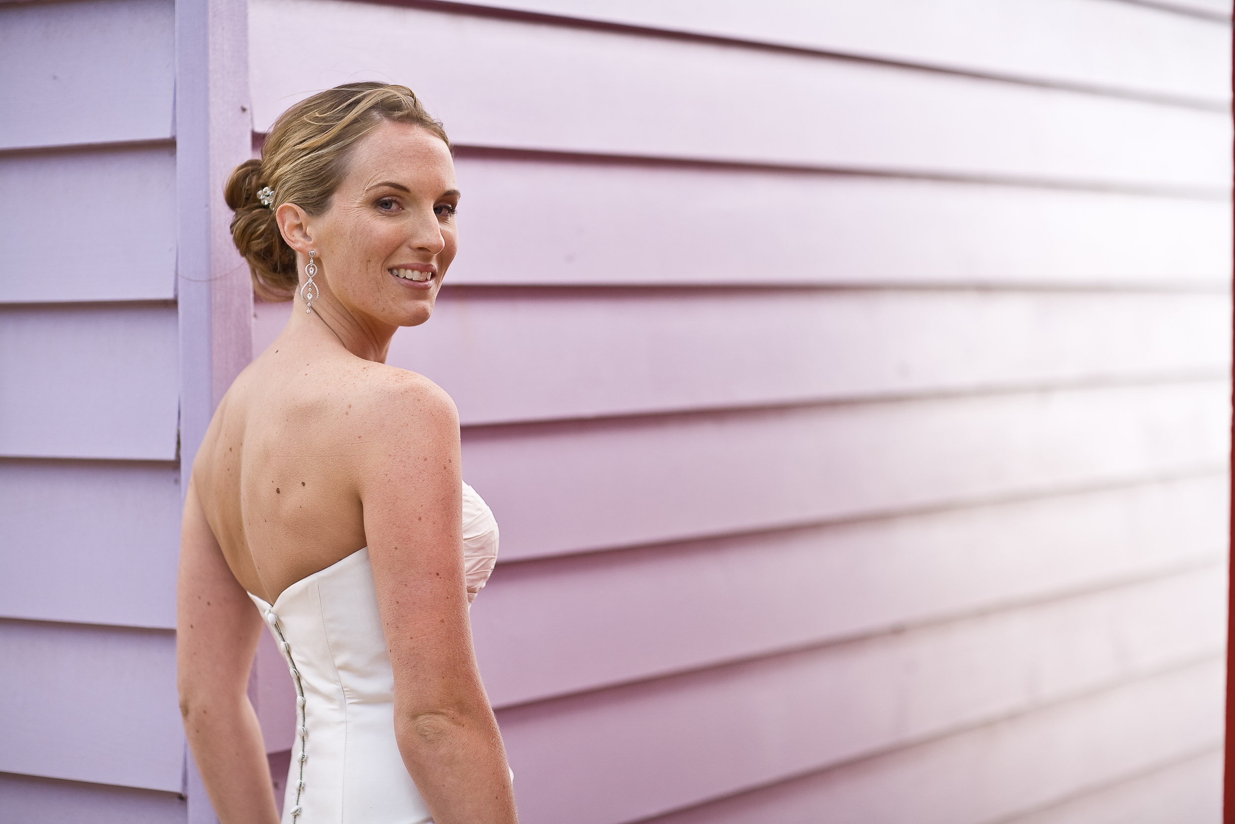 Half length portrait of a bride against a pink bathing hut, Brighton.