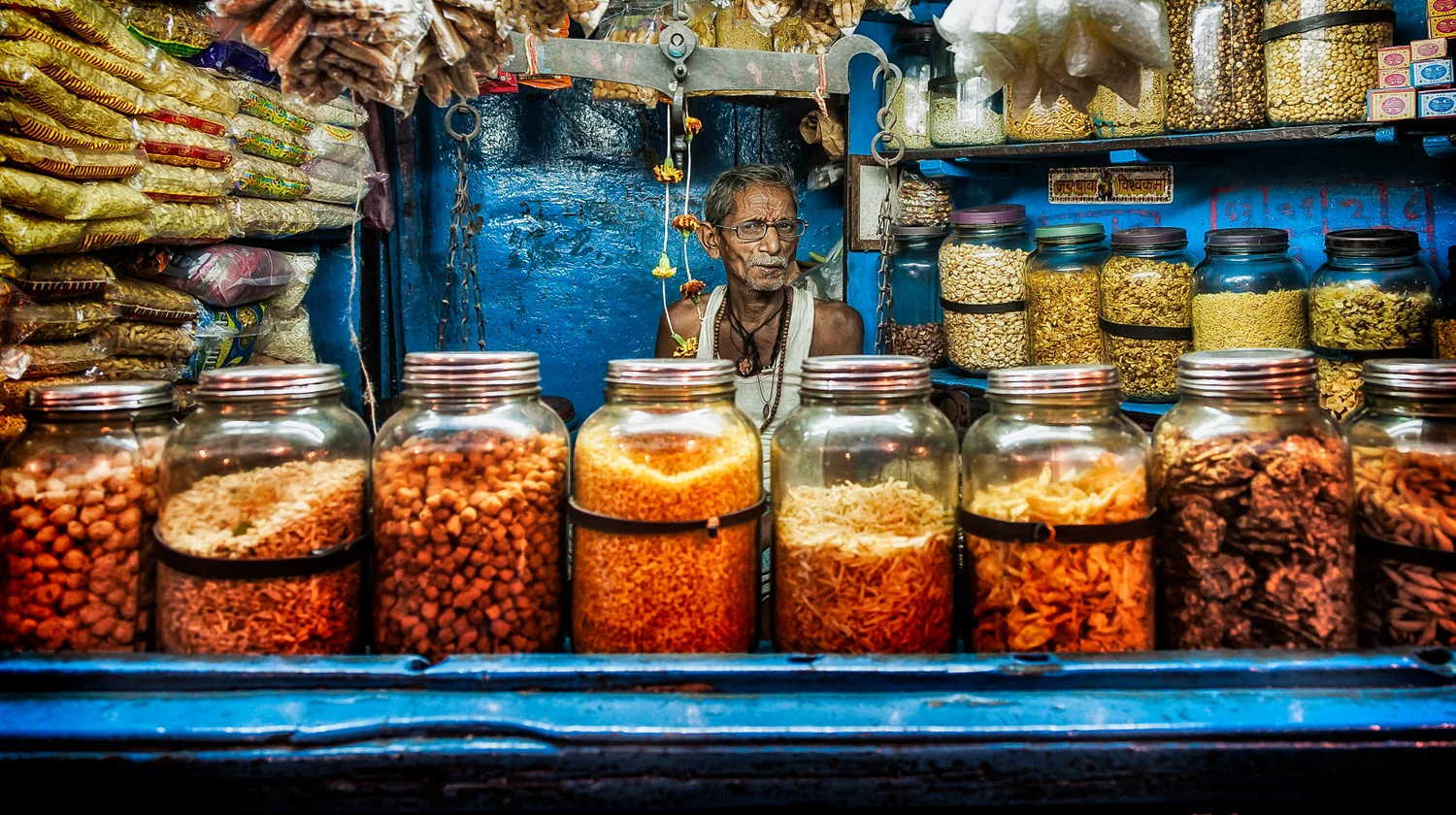 A retailer , amidst a sea of color, in his store in Kolkata, India .