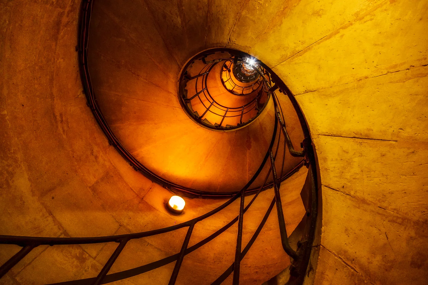 A worms eye viewpoint provides a dramatic perspective of the stairwell that leads up to the top of the Arc de Triomphe in Paris, France. This photo was made with the very capable Canon 5D Mark II camera .