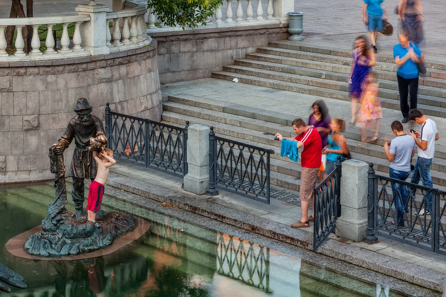 A father photographs his young boy standing next to a statue near the Kremlin in Moscow, Russia .
