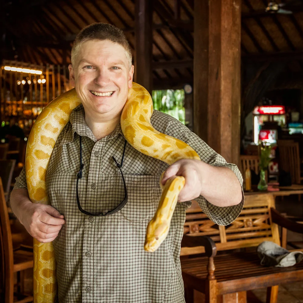 Glenn Guy , photographer and owner of the Travel Photography Guru website and blog, holding a python at Bali Zoo in Bali, Indonesia.