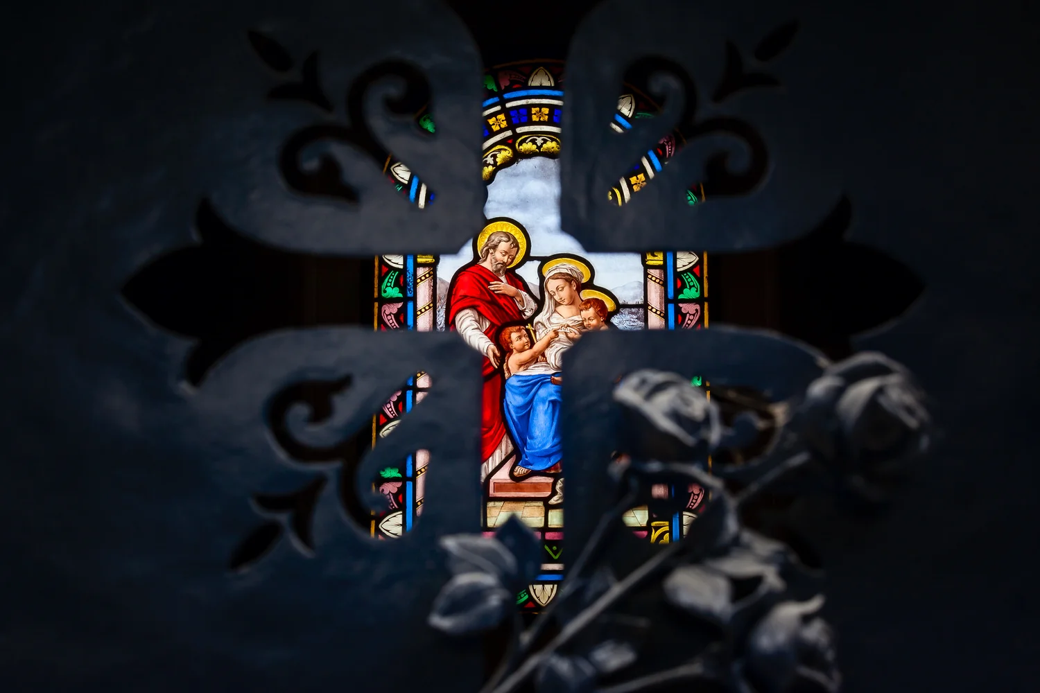 Unconventional subject matter discovered by photographing through the shape of a Christian cross towards a stained glass window at Pere Lachaise Cemetery in Paris, France.