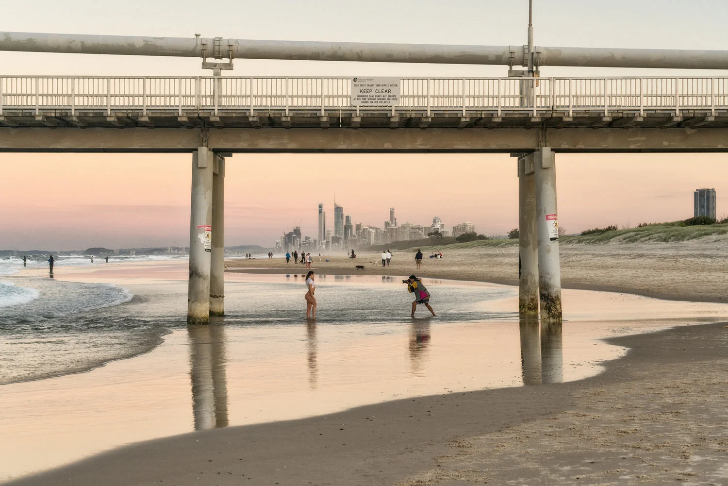 A photographer and swimsuit model under the Sand Pumping Jetty at The Spit on the Gold Coast , Australia.