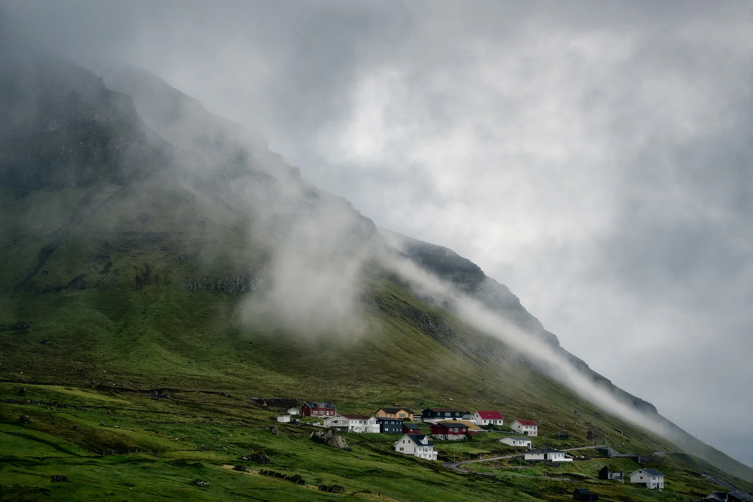 Mist and and rain clouds hover over the village of Kunoy on the island of Kunoy in the Faroe Islands .