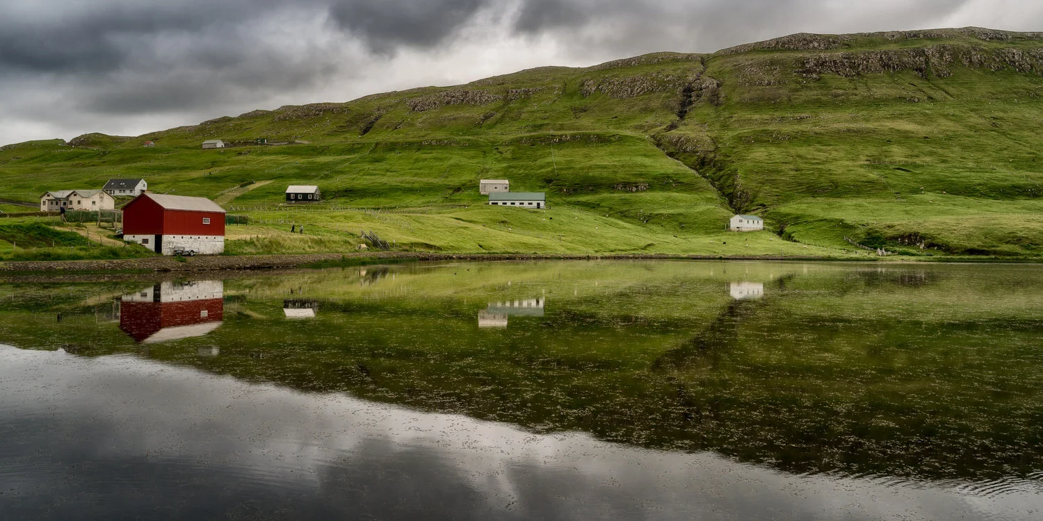 Serene scene of houses around a lake on Suduroy, Faroe Islands .