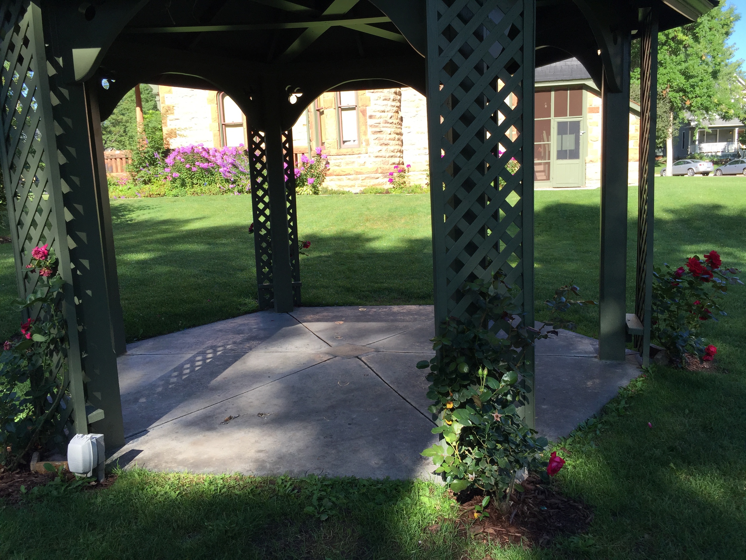  A summertime view of the restored gazebo, complete with heirloom roses in bloom. The dedication plaque is visible in the center of the gazebo floor. 