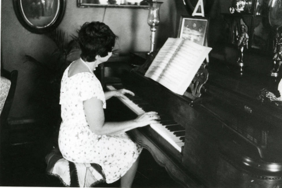  Circa 1980 - Black and white photograph of the interior of the Avery House with June Bennett playing the piano; 328 West Mountain Avenue; Fort Collins, Colorado. 