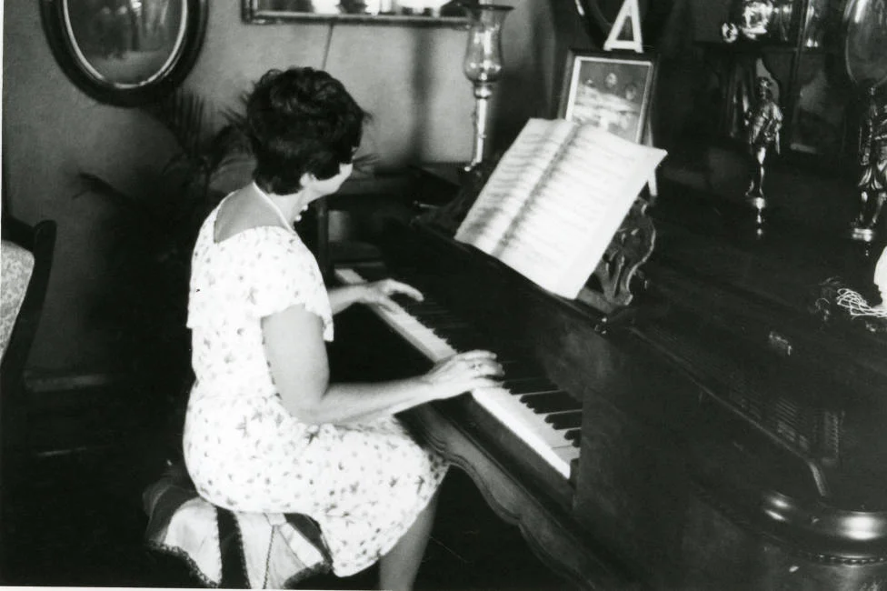 Circa 1980 - Black and white photograph of the interior of the Avery House with June Bennett playing the piano; 328 West Mountain Avenue; Fort Collins, Colorado.