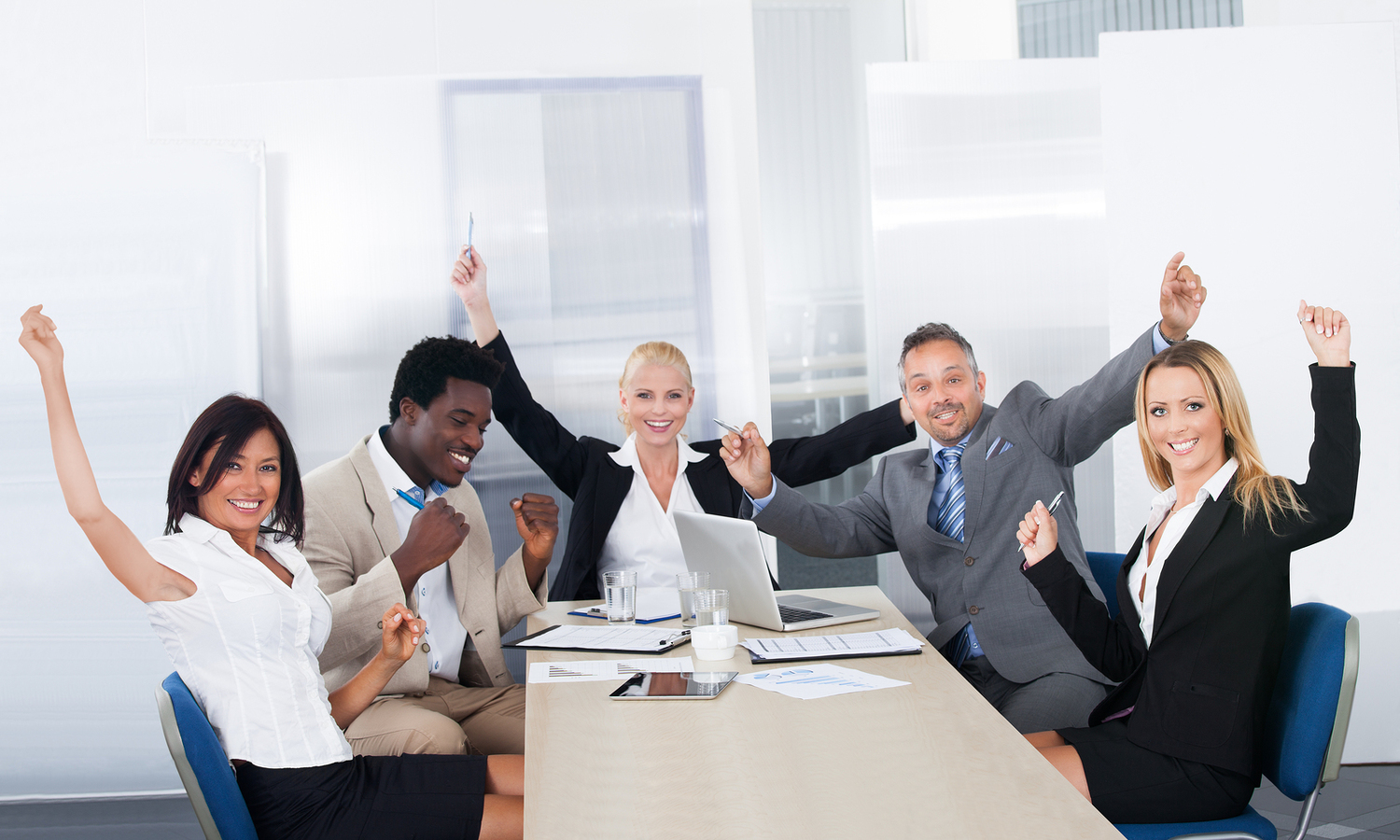 A team of engaged employees sitting at a conference table, celebrating a recent success.