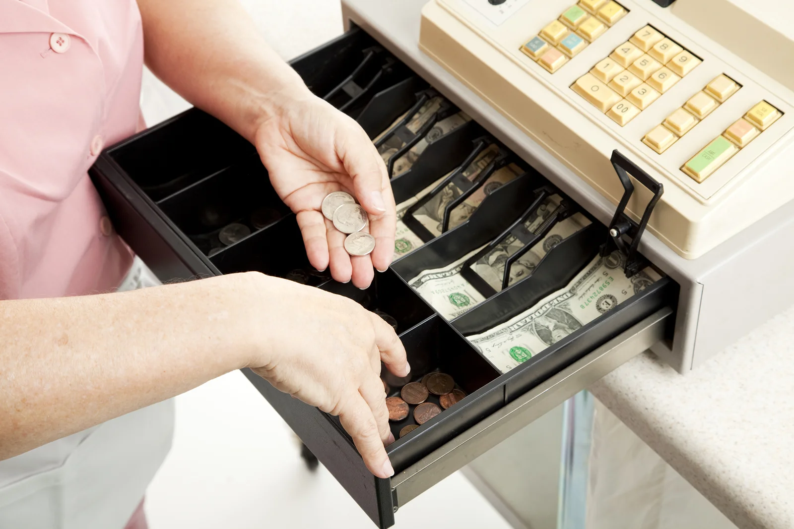 A cashier counting change out of a cash till.