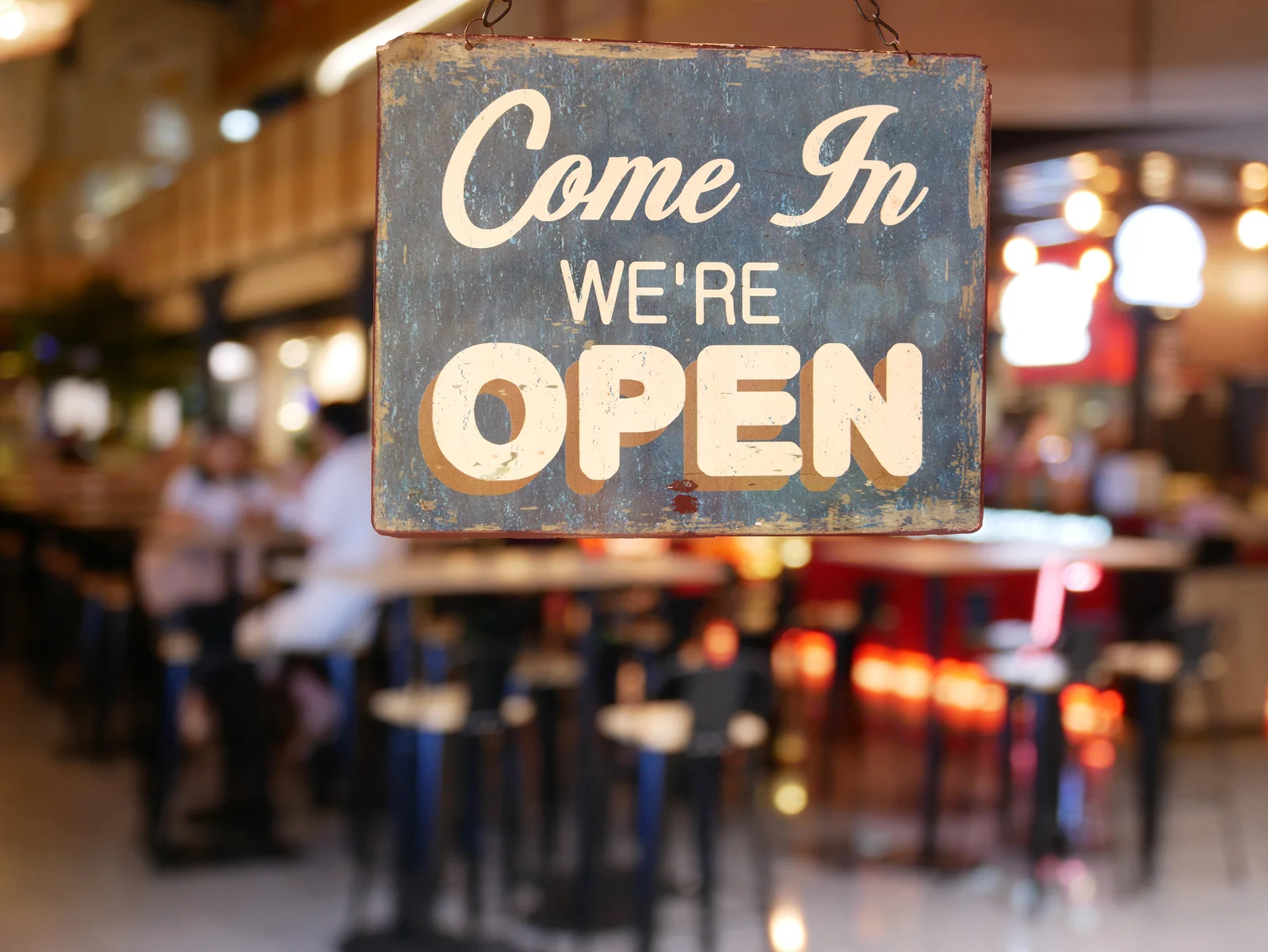Sign hung outside a business that reads "Come In, We're Open."