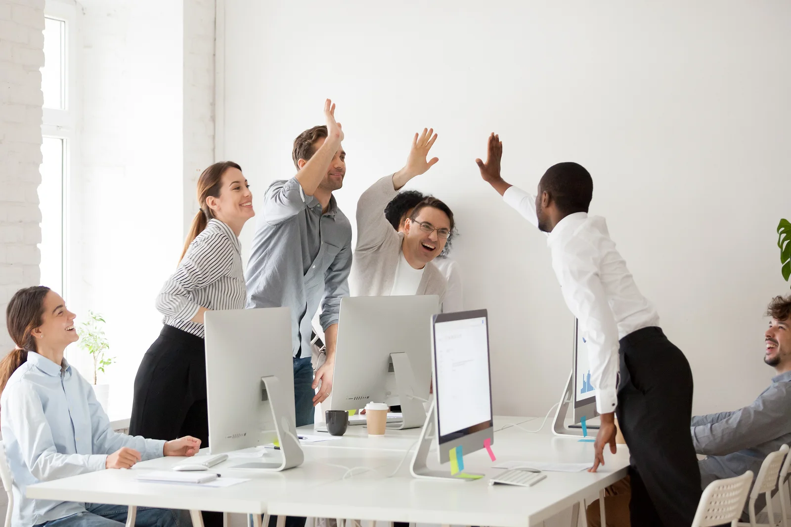 A team of happy customer service employees exchanging high fives.