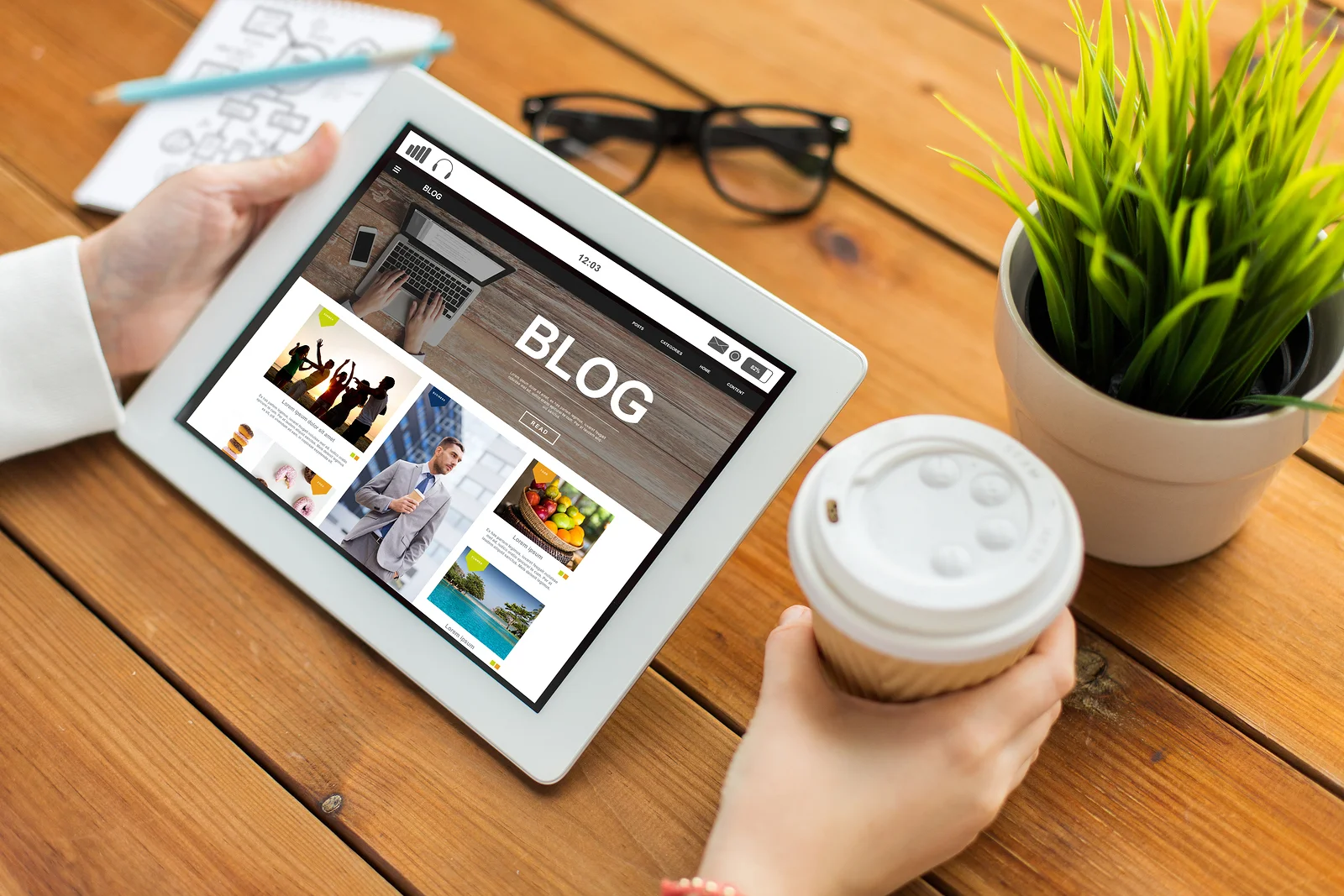 Professional reading a blog on a tablet while drinking a cup of coffee.