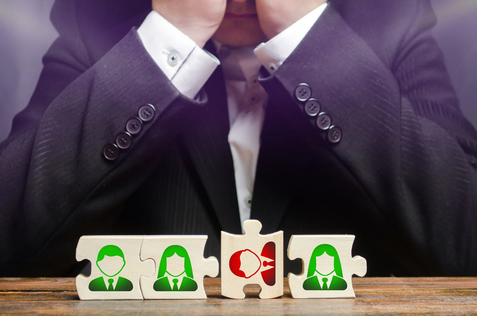 Recruiter evaluating puzzle pieces representing employees. One piece clearly does not fit.