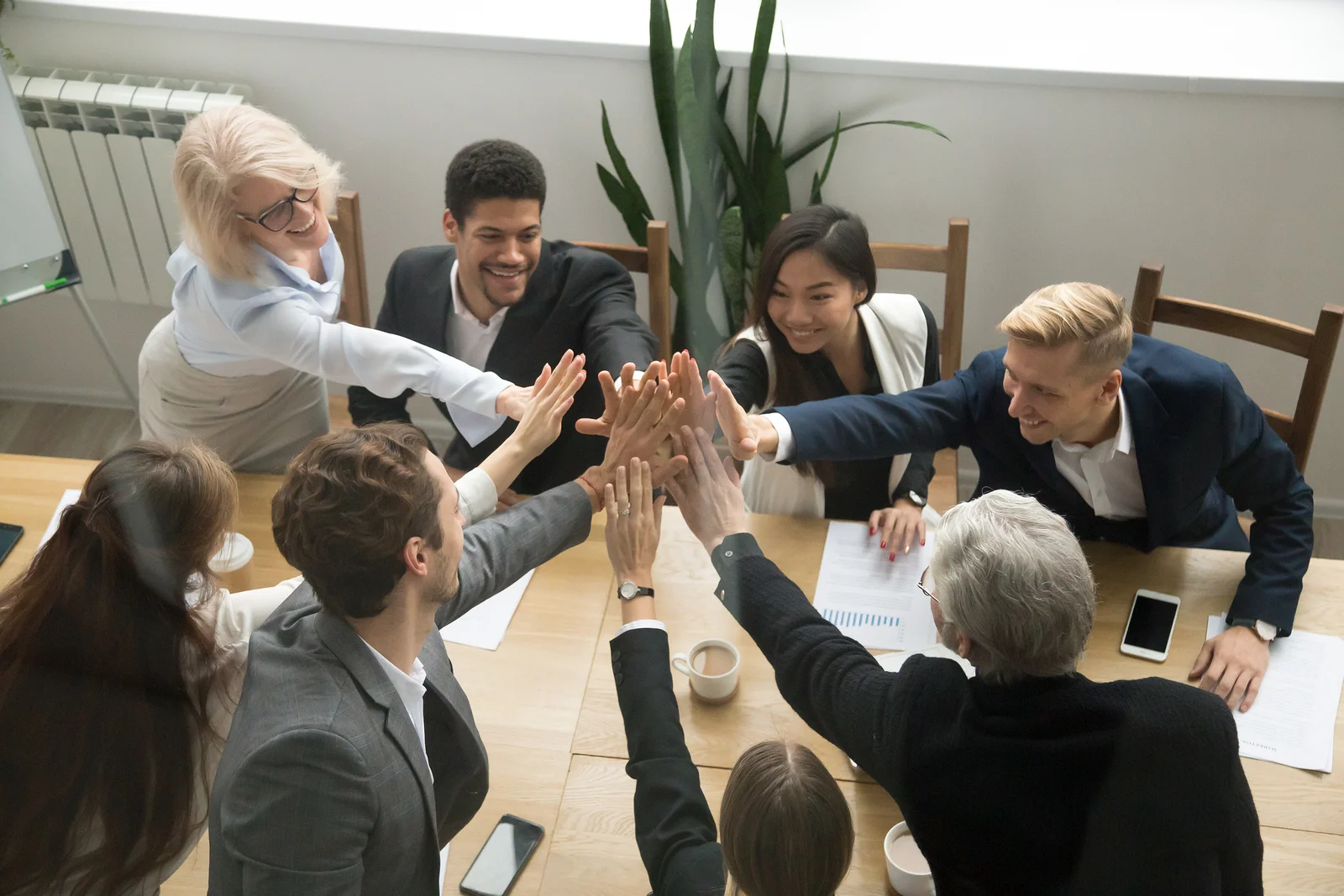 Group of happy coworkers high-giving over a conference table.