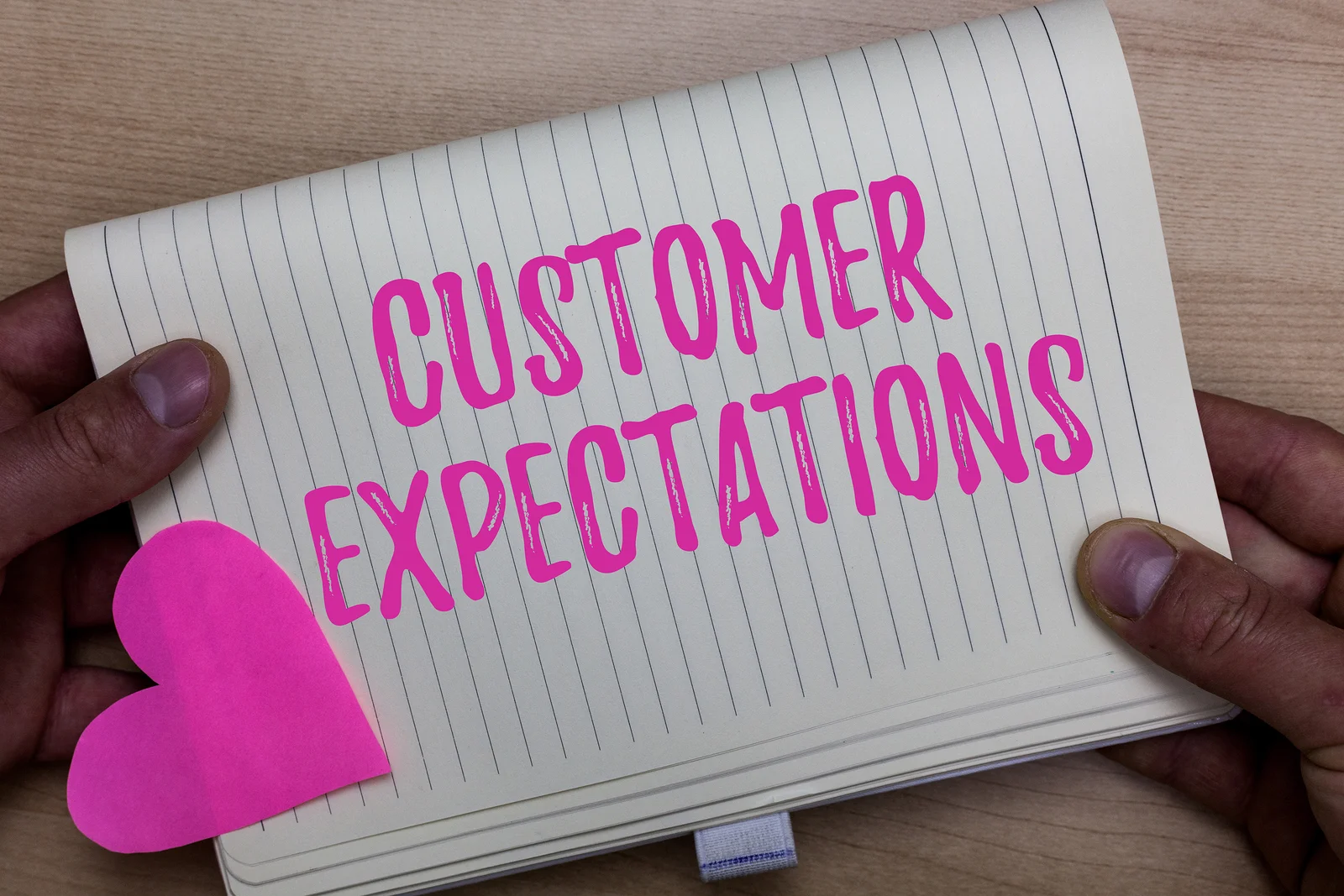 A person holding a notepad with the words “customer expectations” written on it.
