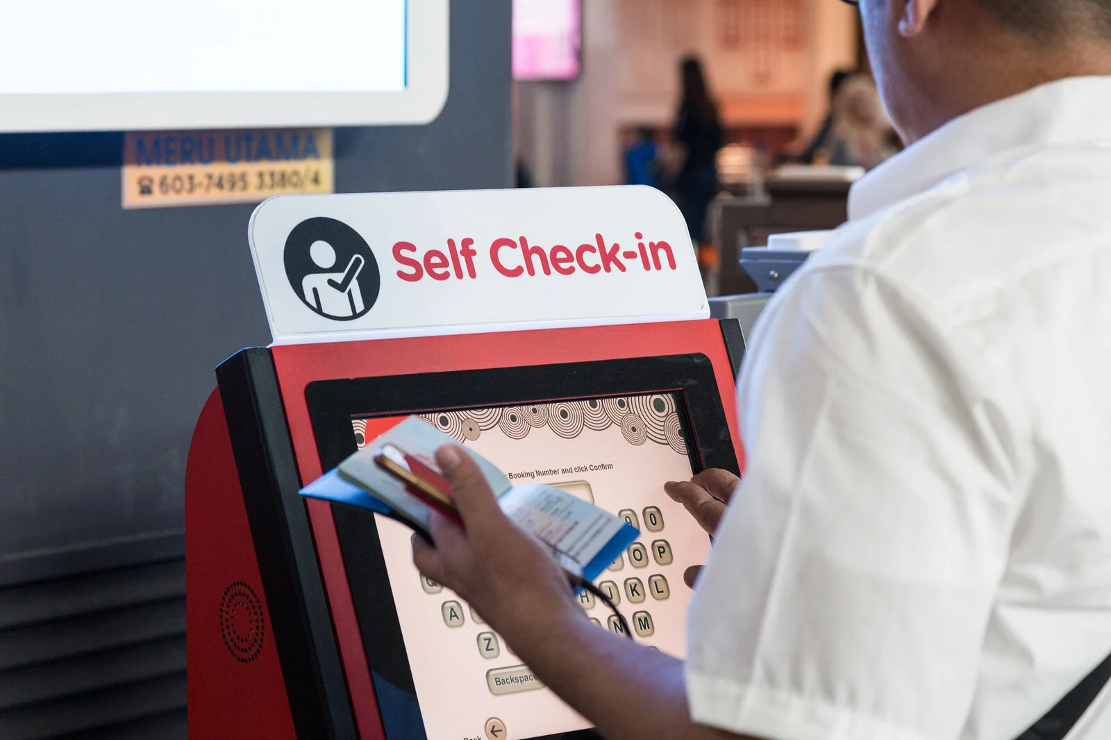 A passenger using a self check-in kiosk at an airport.