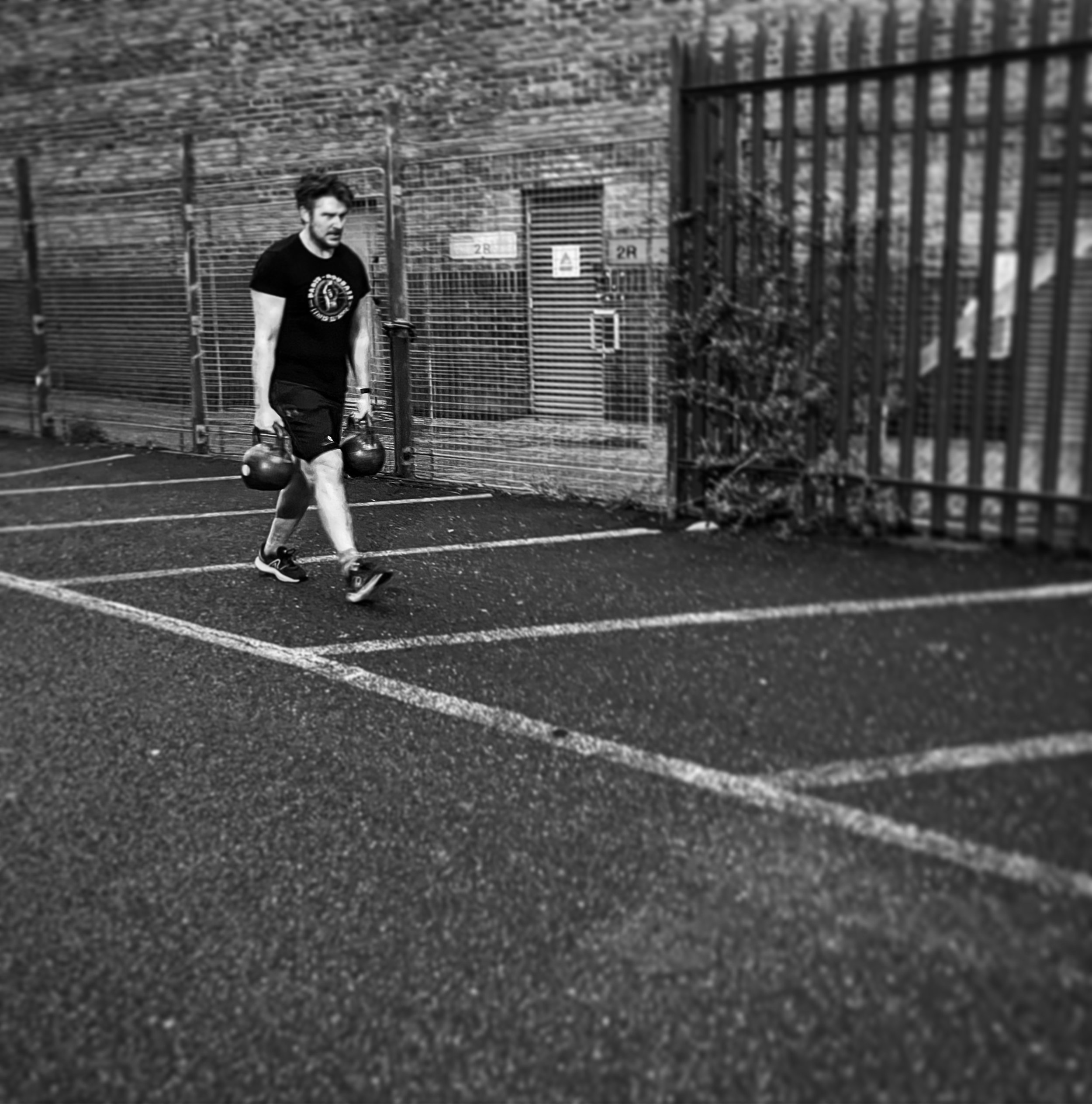 Chris performing a heavy farmers walk during strength training in Deptford