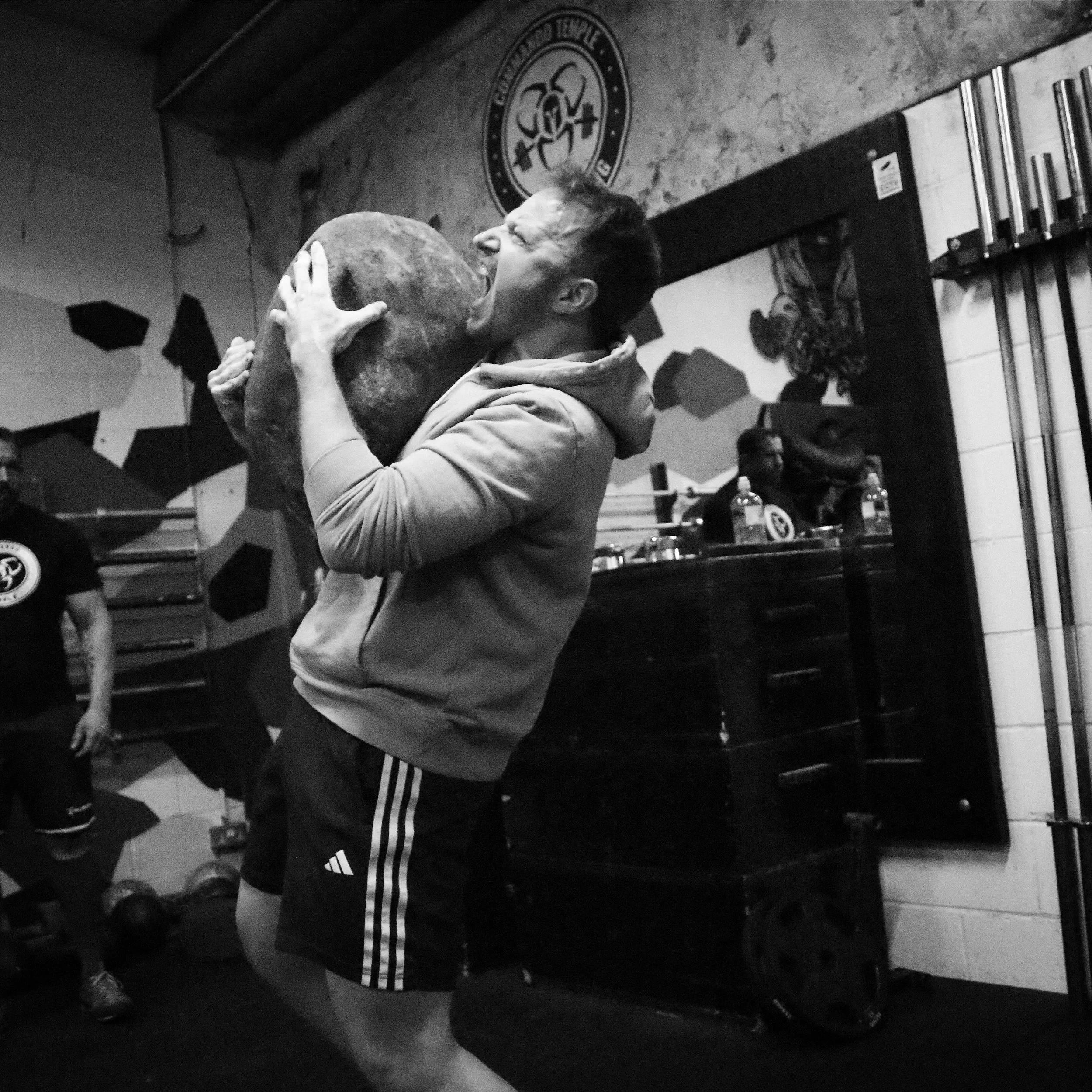 Johnny lifting a natural stone during a strength competition at the Commando Temple in Deptford