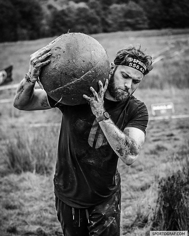 Sam carrying an Atlas stone on his shoulder during a Spartan Race