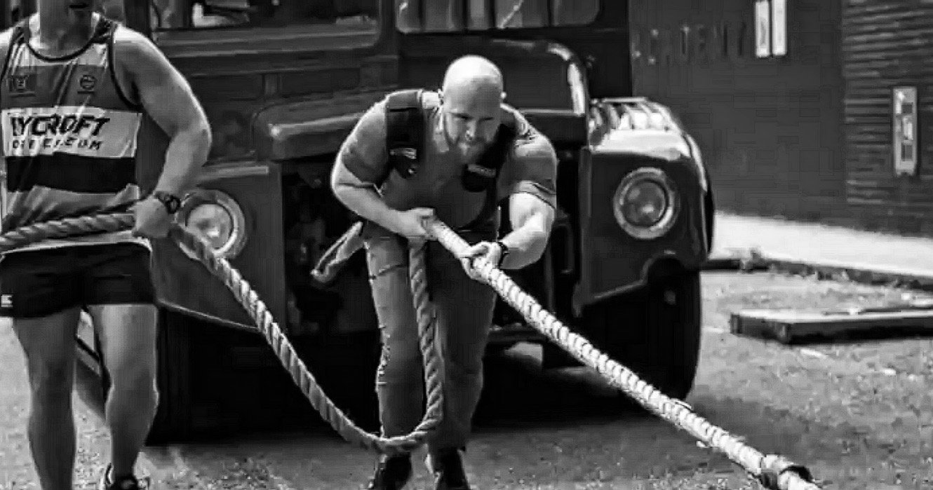 Strength coach Ben Waters pulling a bus during a strength challenge