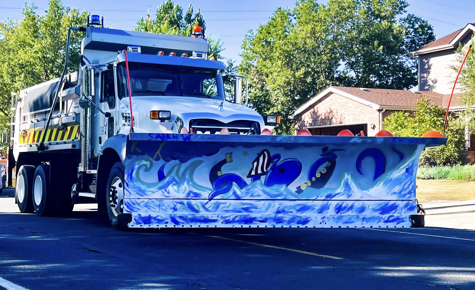 A large white utility truck with colorful graffiti art of an octopus in a sea wave scene on its front bumper.