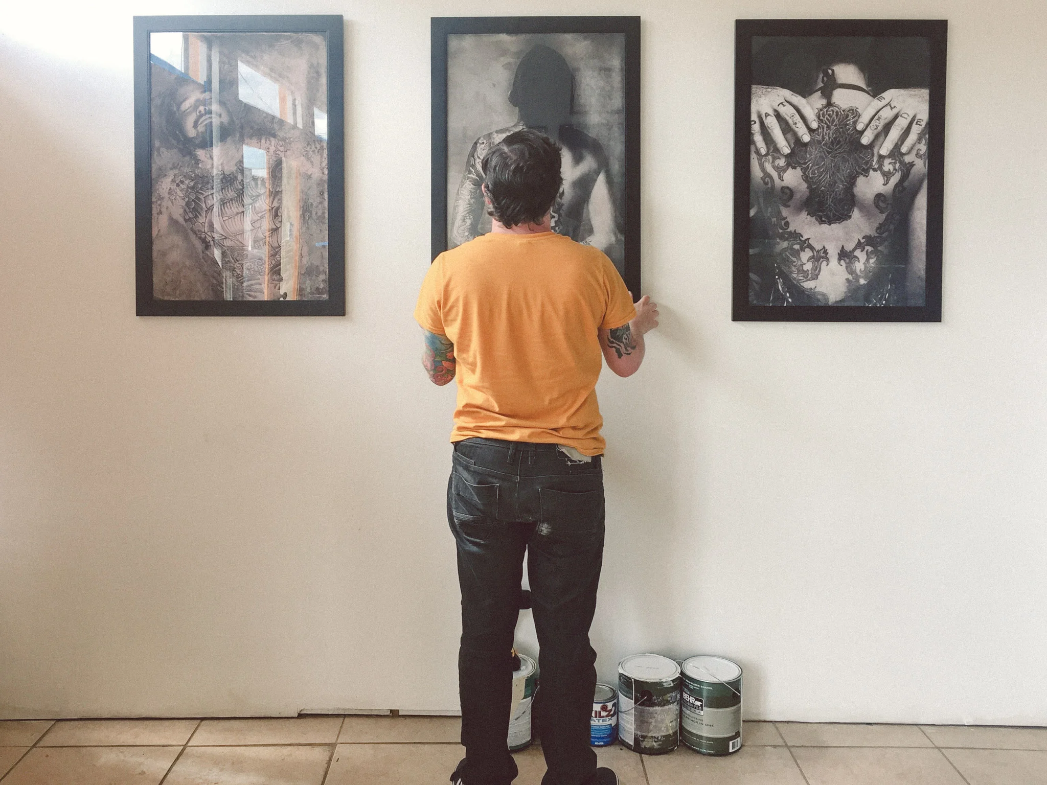 Adam Montegut of the New Orleans Tattoo Museum hanging prints from the Black Ink photo series.