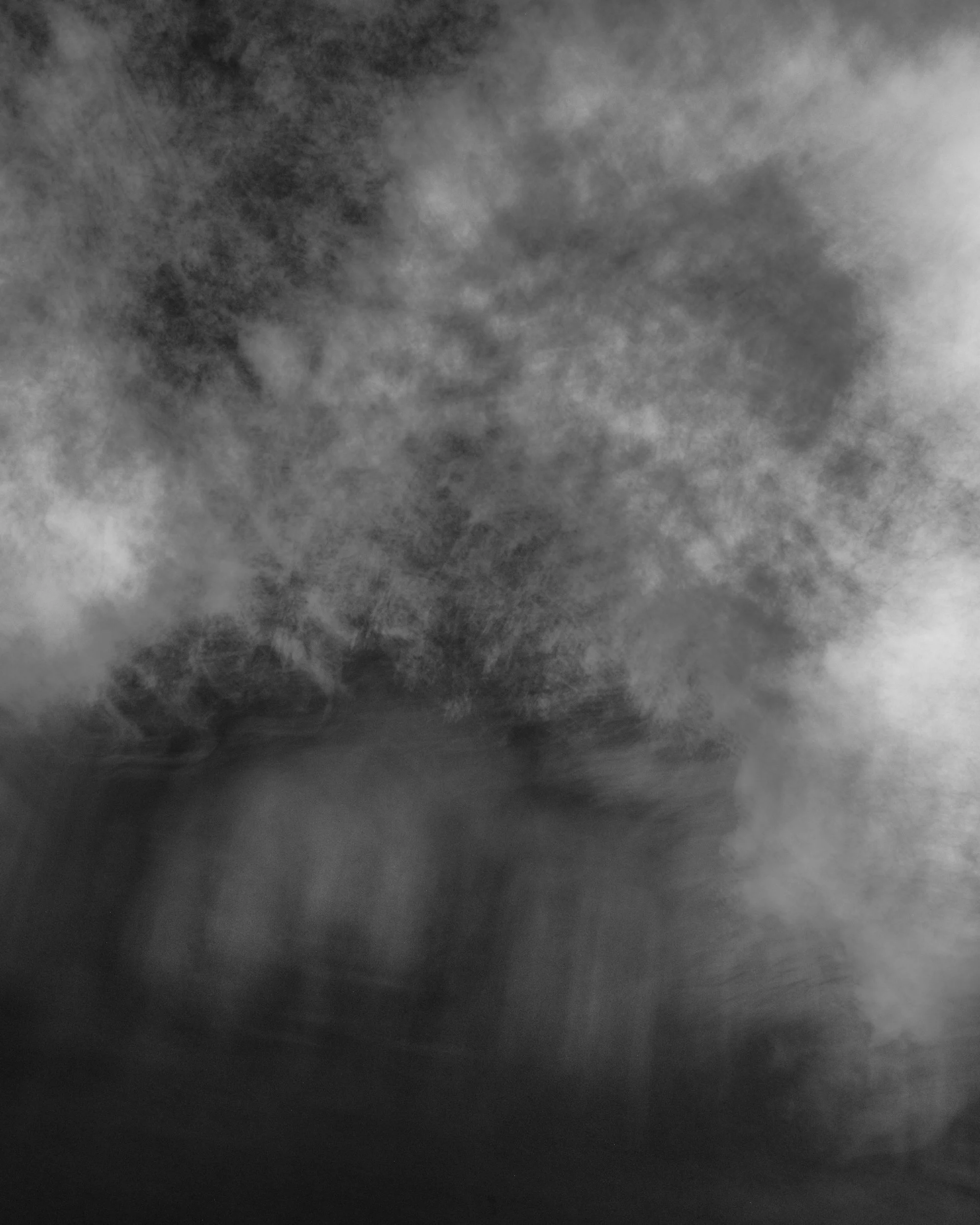 Black and white abstract photograph of cloud-like formations or smoke with varying shades of gray