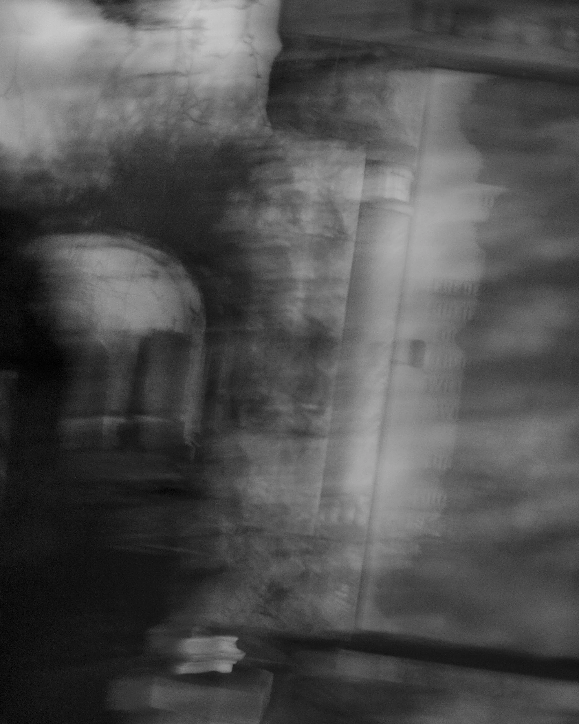 A blurry black-and-white photo of a person sitting on a toilet in a bathroom, with the toilet and some bathroom tiles visible.