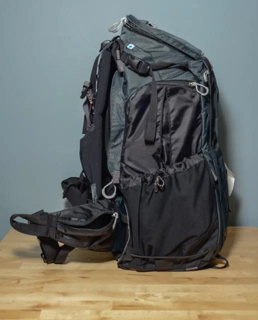 This side has the compartment for holding a hydration bladder (Camelback) and an exit point for the straw. It also has a mesh pocket for a water bottle or other snacks. Both of these are key for long hikes. The waist belt on this side has a small pocket for stashing a granola bar.