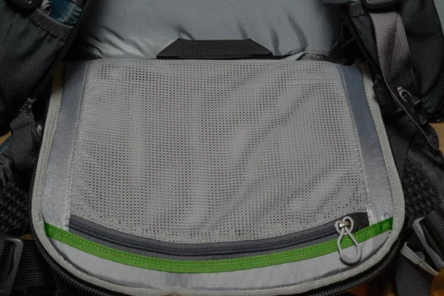 The back pad opens to allow access to the main compartment, meaning you could theoretically access the main compartment without taking the bag off if you rotated the entire bag to your front. This pocket would be a great place to stash a cleaning cloth or other relatively flat items. I wouldn't shove anything too bulky here as it might stick out on your back funny.