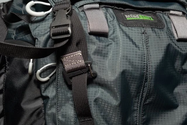 The pocket attaches to one of the many loops on the front. The straps are long enough that I think I could probably shove a bedroll or something underneath the pocket and use that tension to hold it in place. 