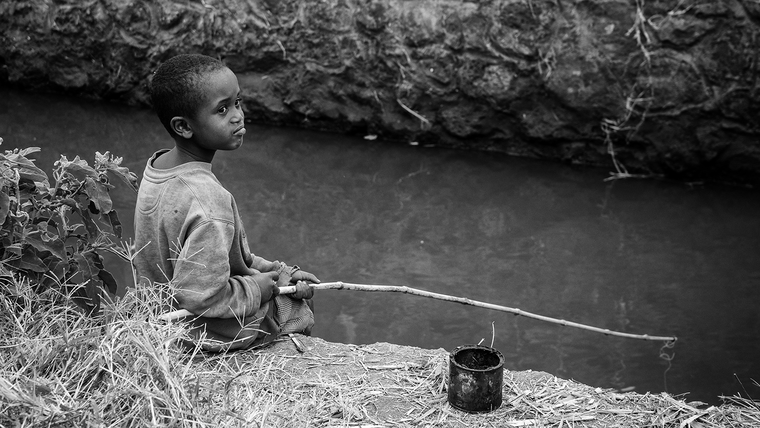 A young boy fishing in one of the canals that supplies water to the rice fields