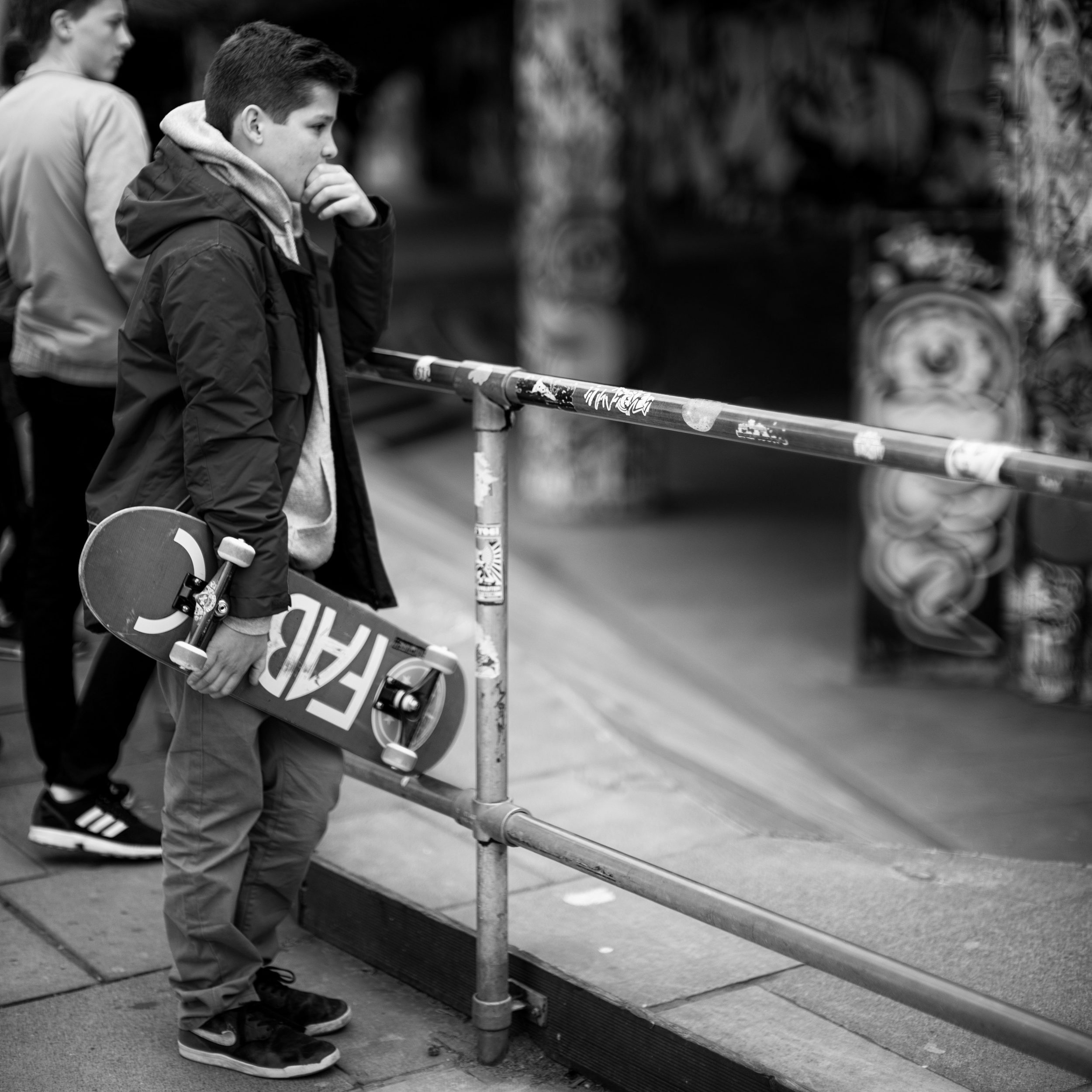 A young skater watches others in the park