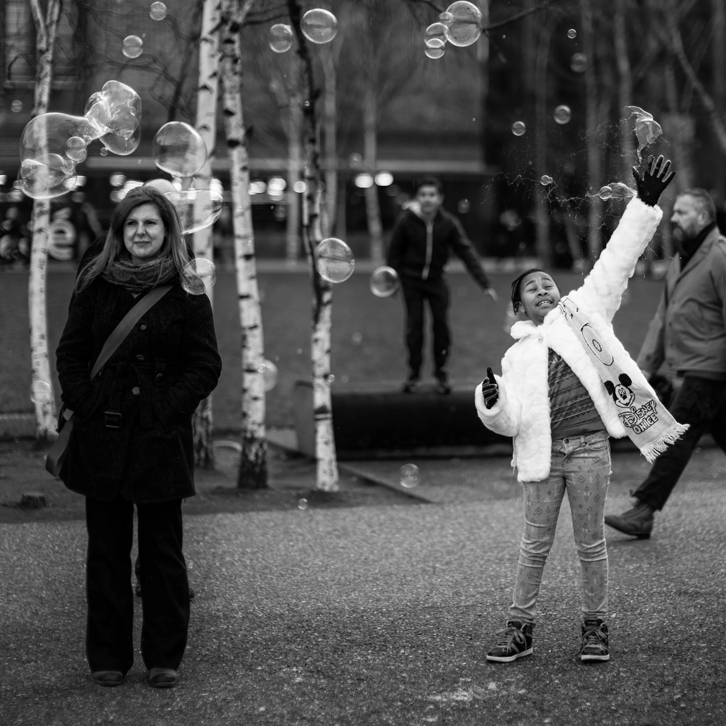 A little girl pops bubbles along the Southbank Center boardwalk