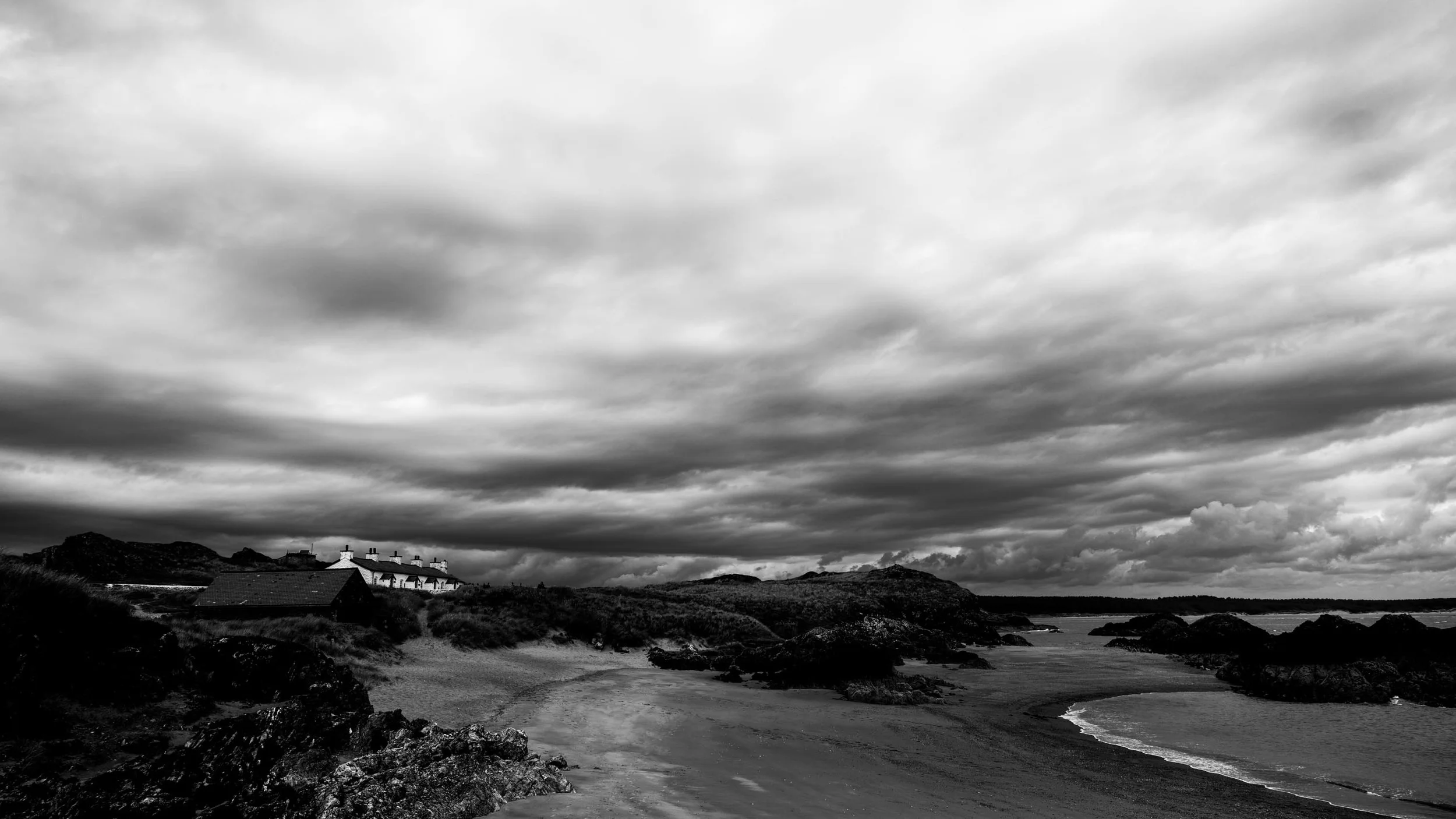 Small boat houses line parts of the coast as storm clouds bear down on the island