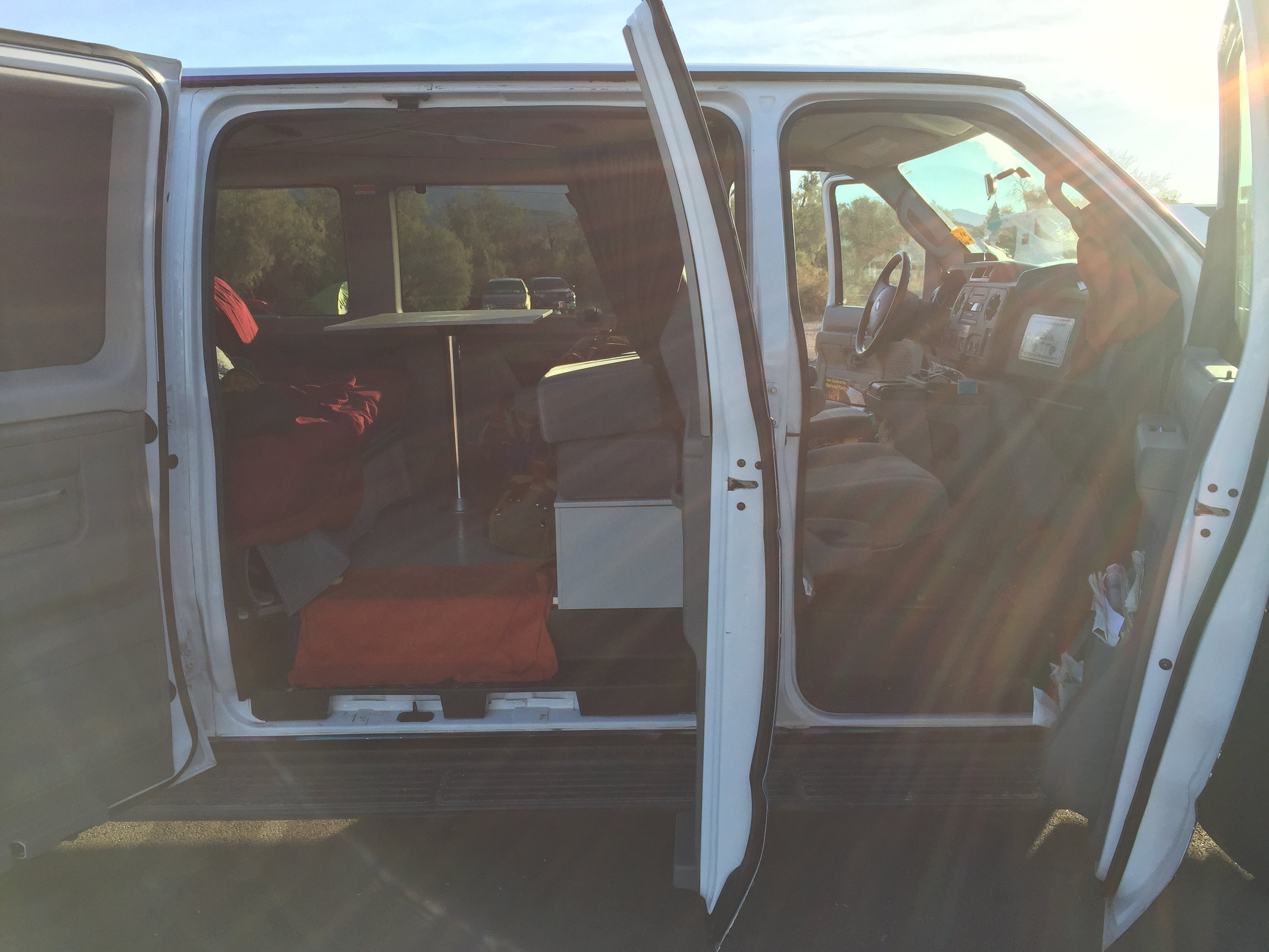 It may not look it, but the van is super clean. The orange towel on the ground served as a doormat. You can also see where we stacked the cushions on the right to create more storage area in the wooden box below.